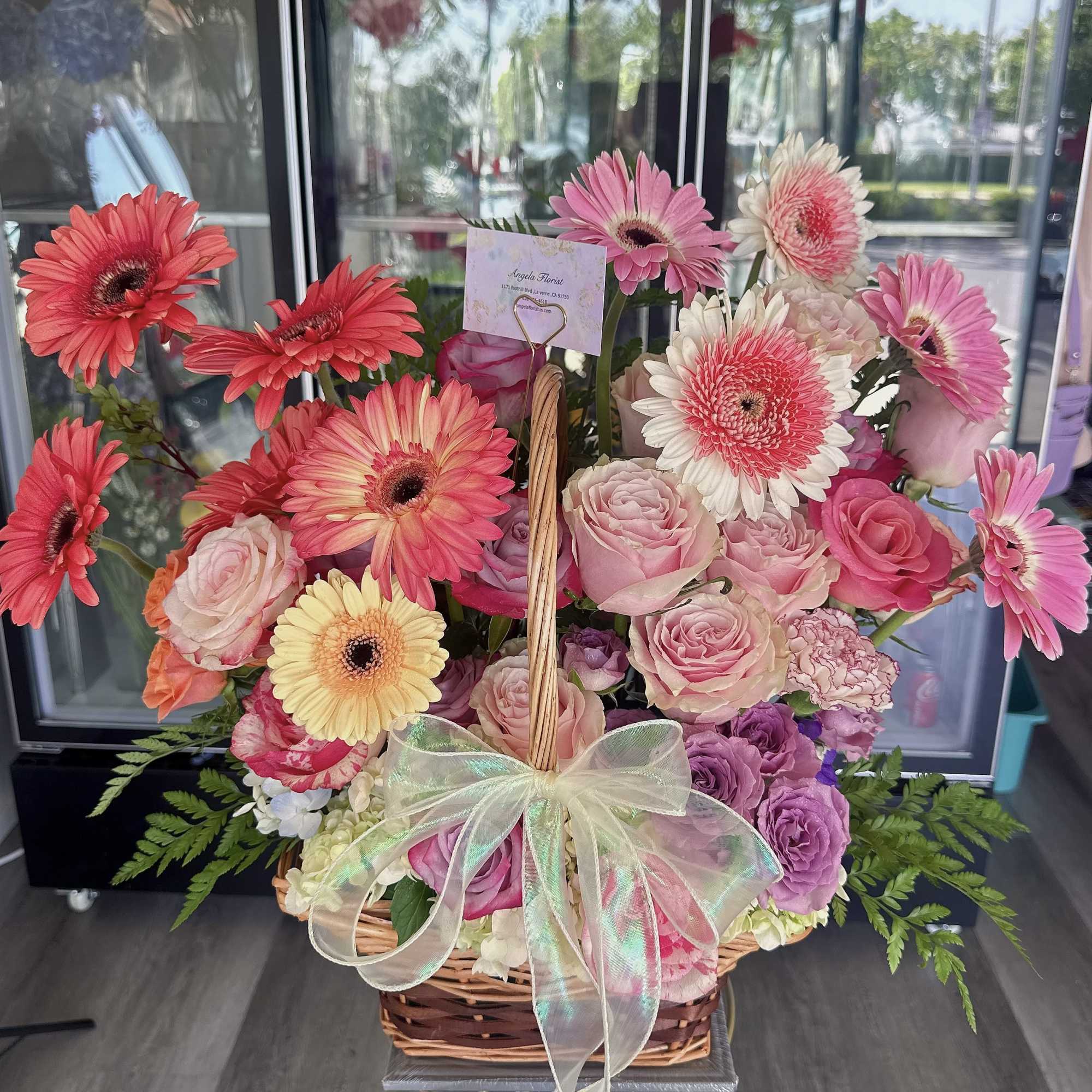 Basket arrangement of pink gerberas and roses with a sheer bow