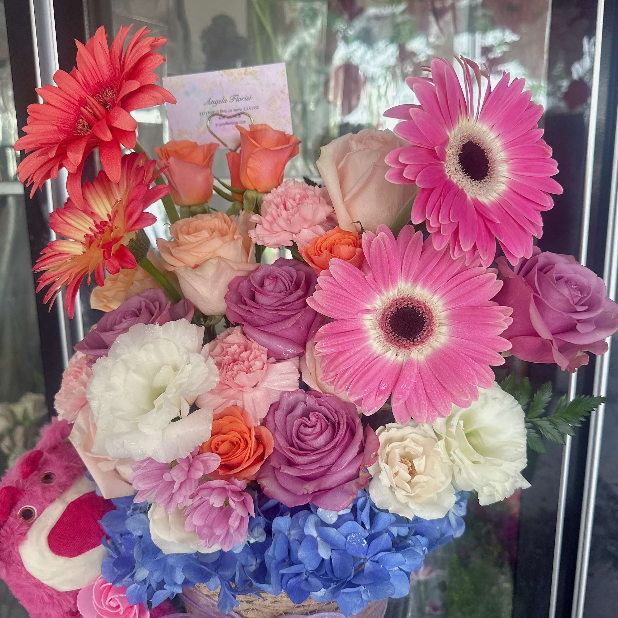 Colorful bouquet with gerbera daisies, roses, hydrangeas, and a plush bear