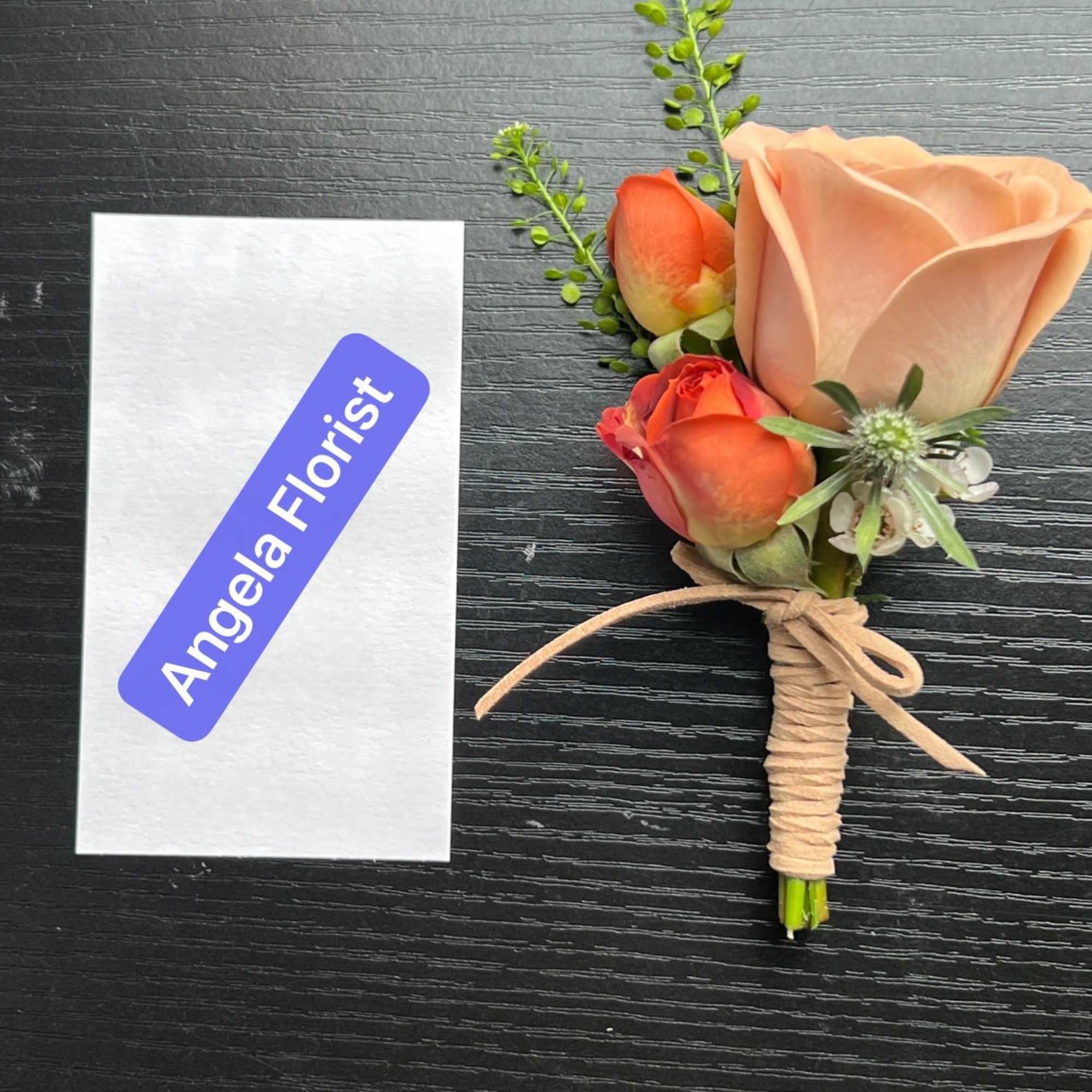 Small boutonniere with peach and orange roses tied with twine