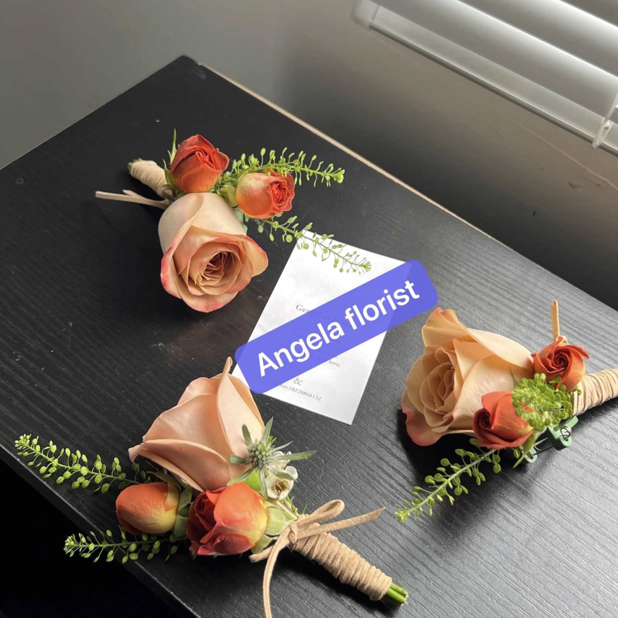 Three rose boutonnieres with peach and orange blooms on a table