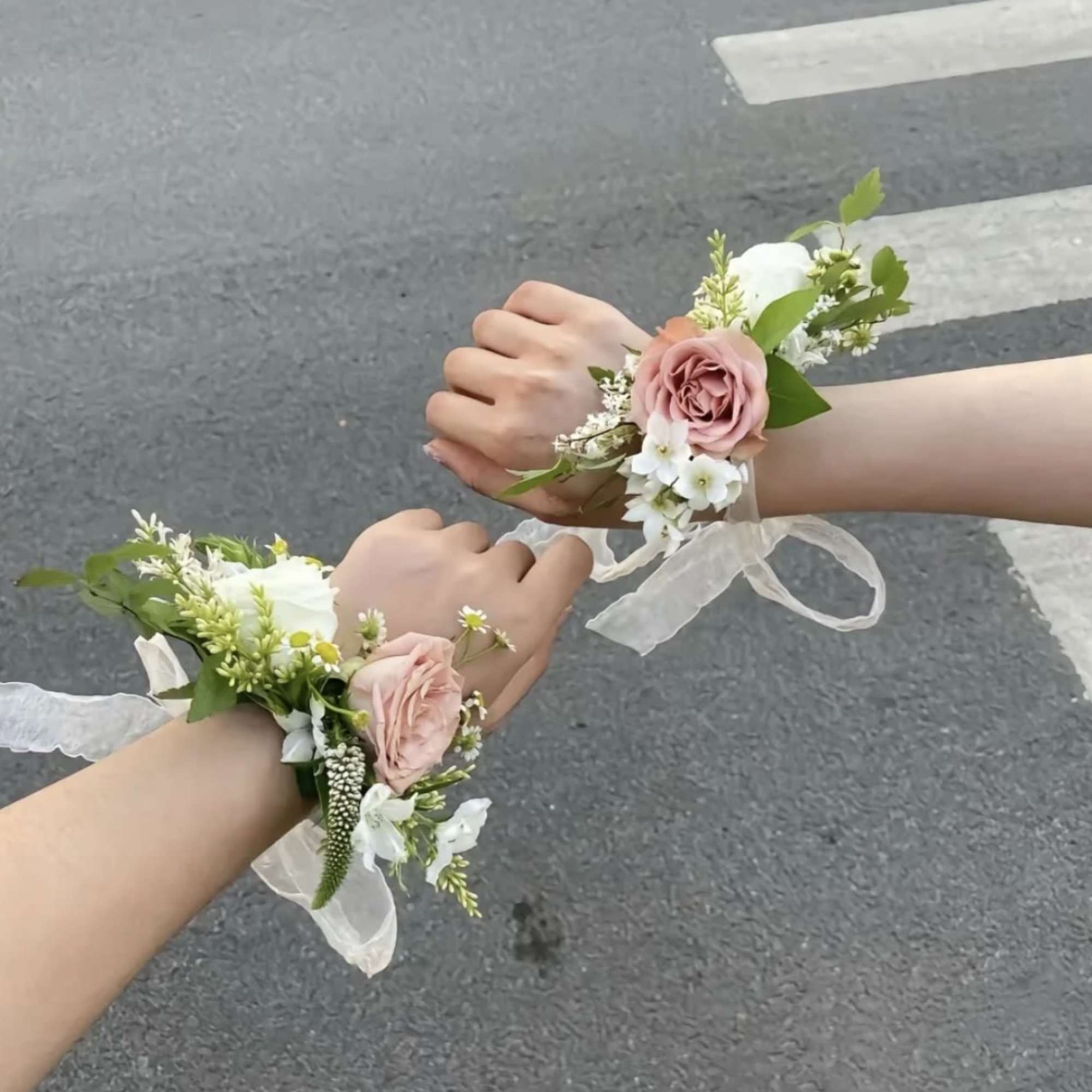 Two floral wrist corsages with pink roses and white flowers