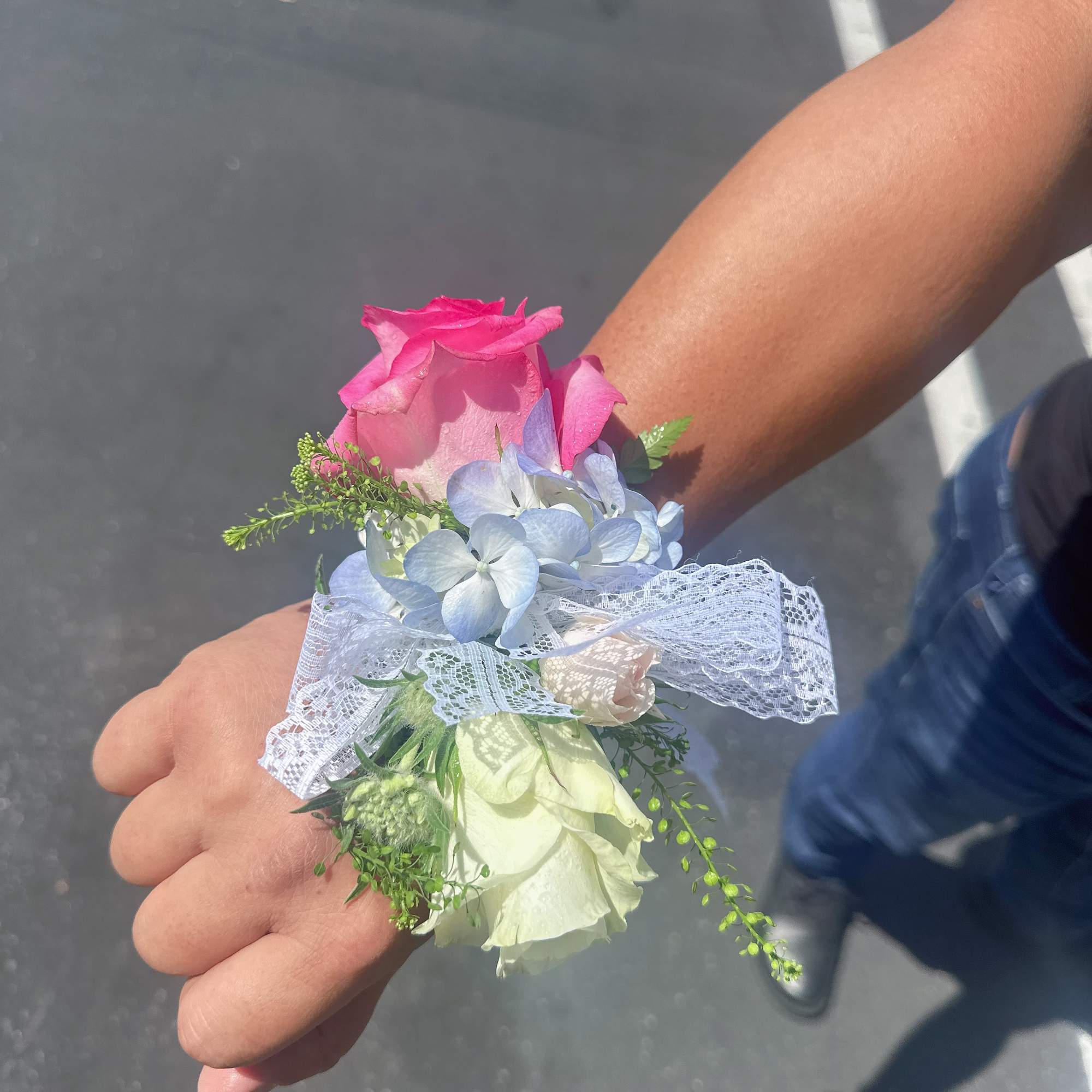 Pink rose corsage with pale blue flowers and white lace ribbon