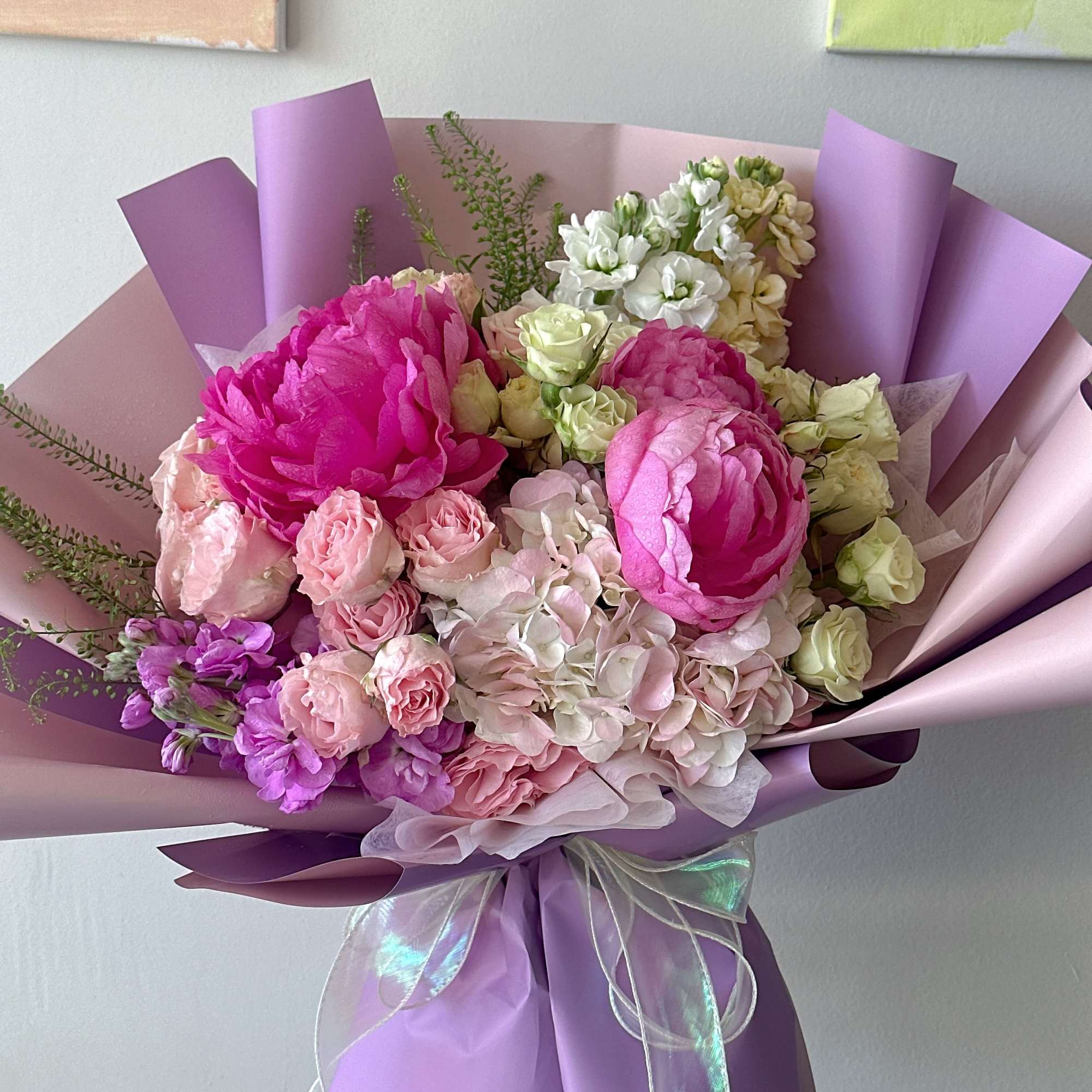 Bouquet of pink and white flowers wrapped in lavender paper