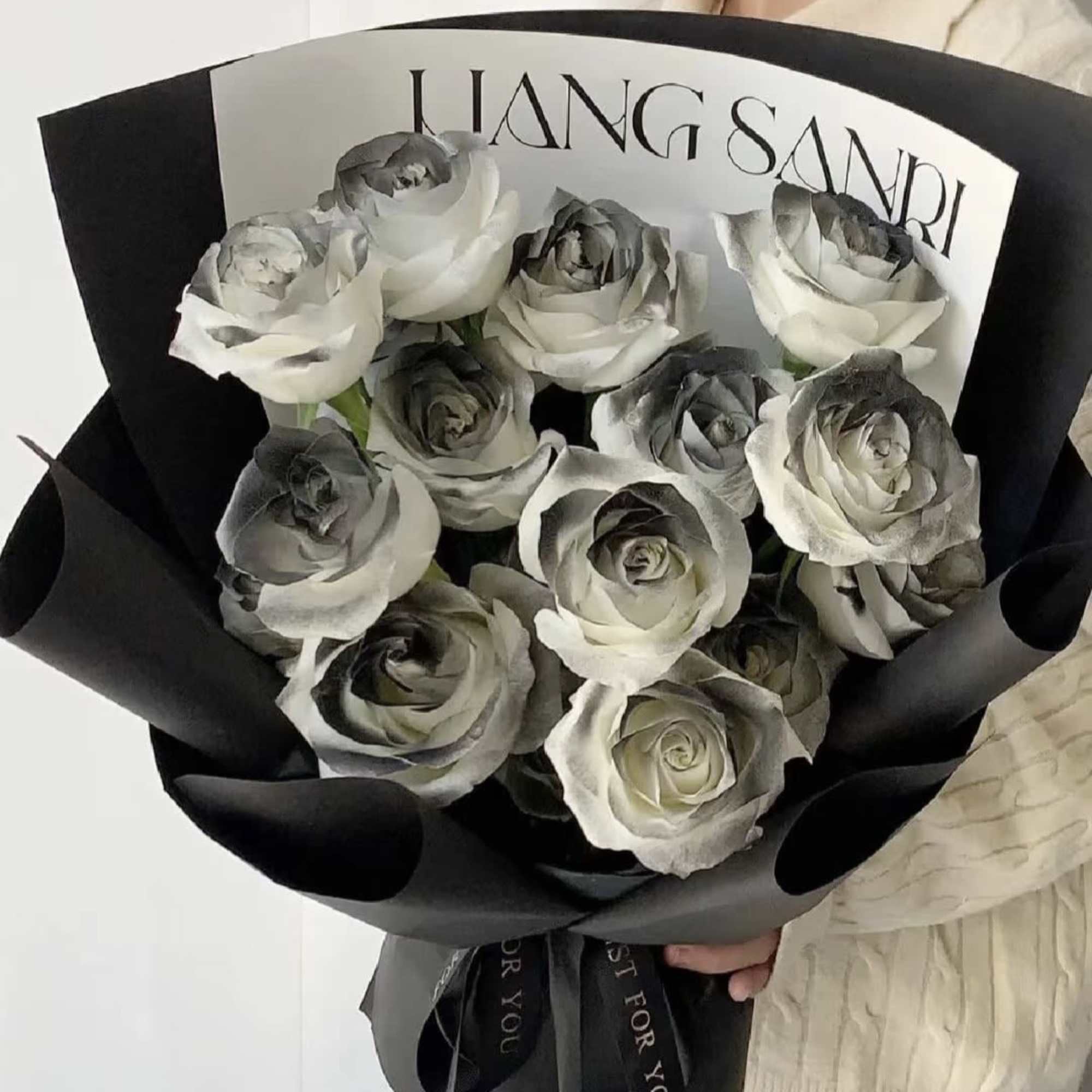 Bouquet of white and gray roses wrapped in black paper