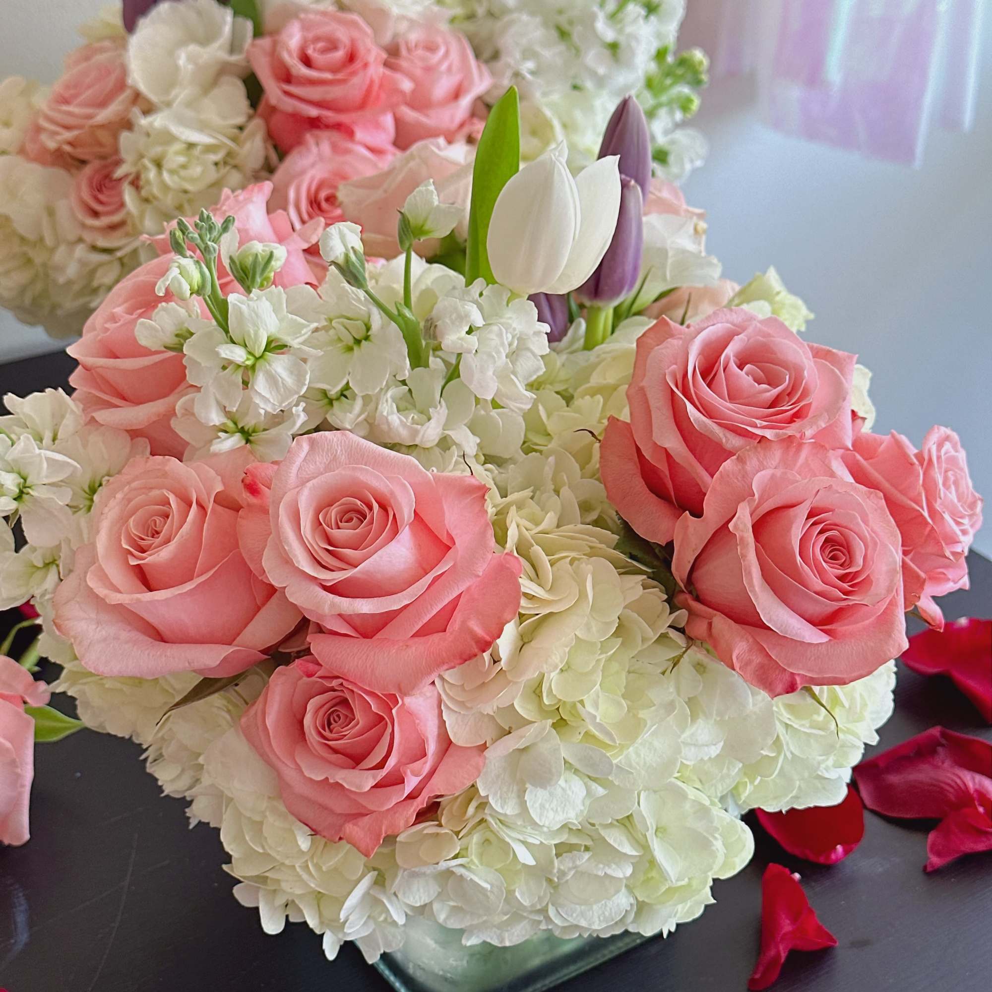 Pink roses and white hydrangeas in a glass vase with purple tulips