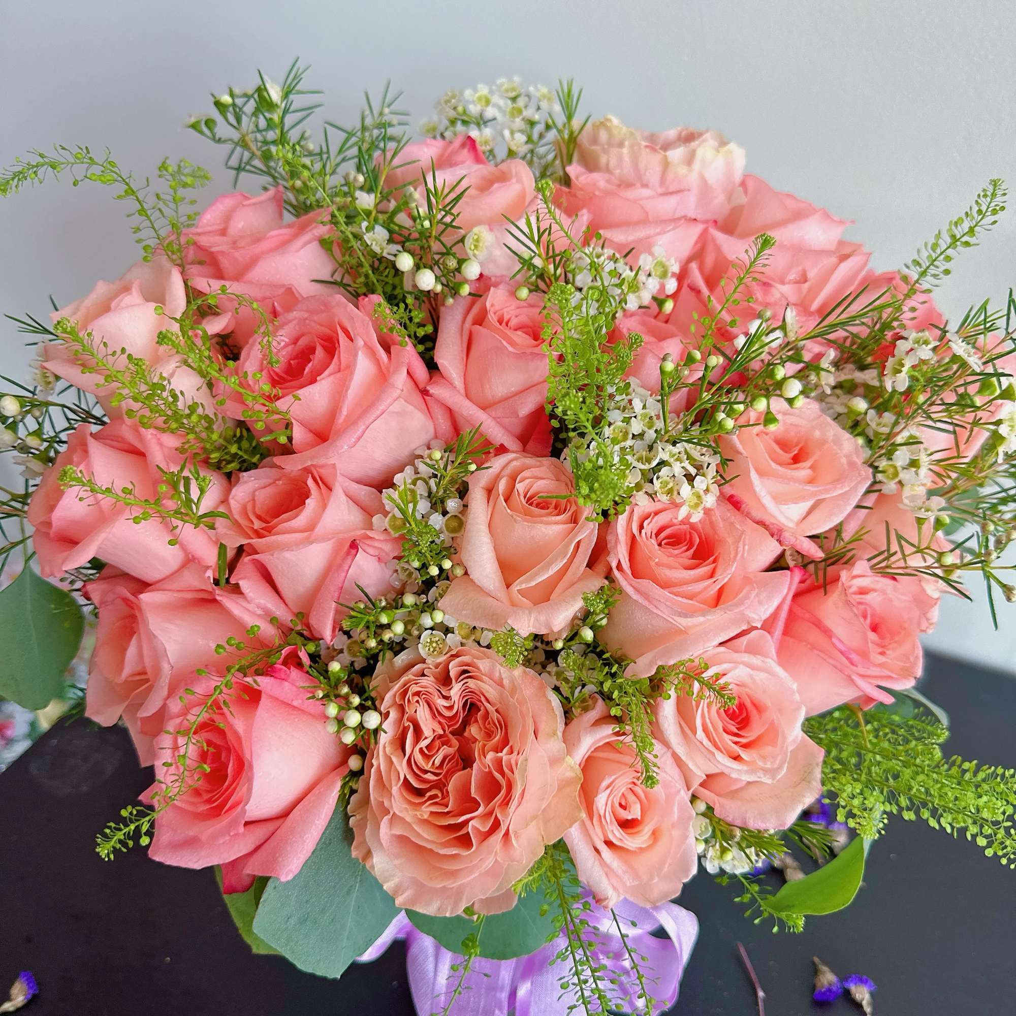 Pink rose bouquet with white filler flowers and a lavender ribbon
