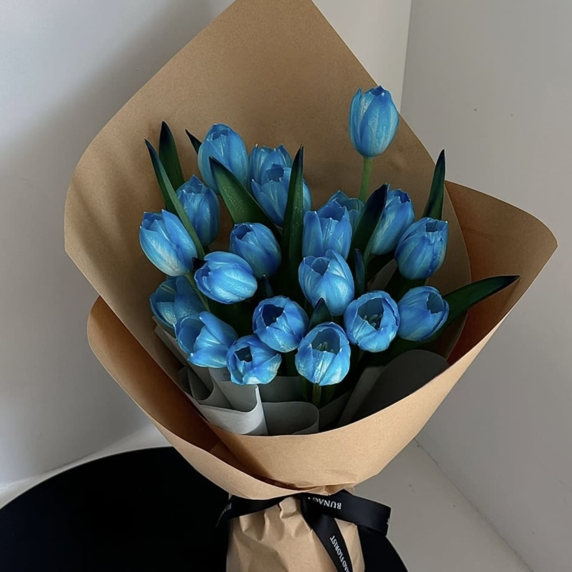 Bouquet of bright blue tulips wrapped in brown paper