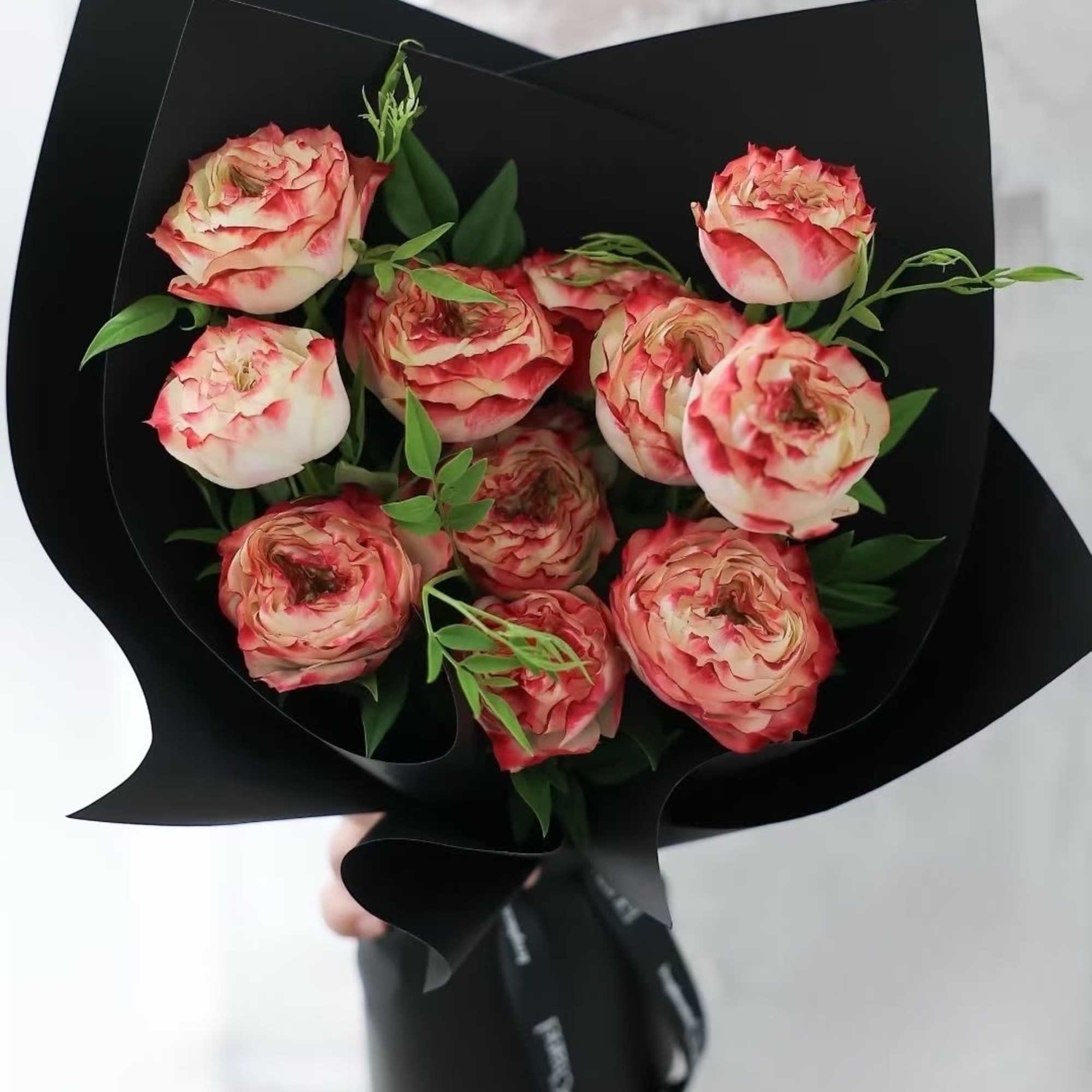 Bouquet of pink and cream roses wrapped in black paper
