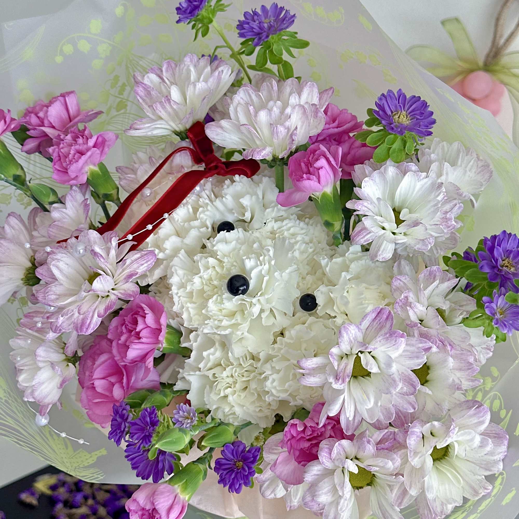 Bouquet of pink, white, and purple flowers wrapped in translucent paper