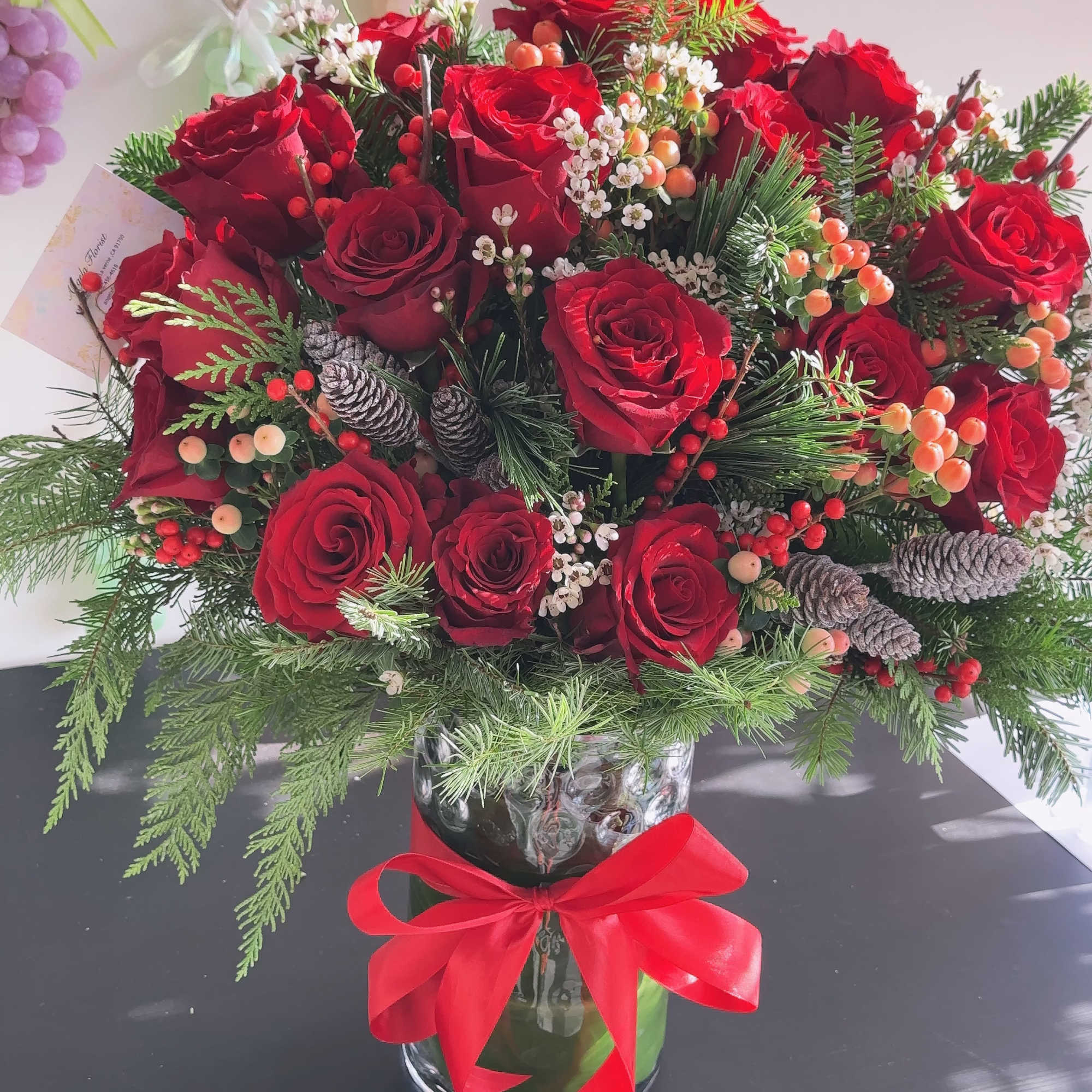 Red roses in a glass vase with pine and berries