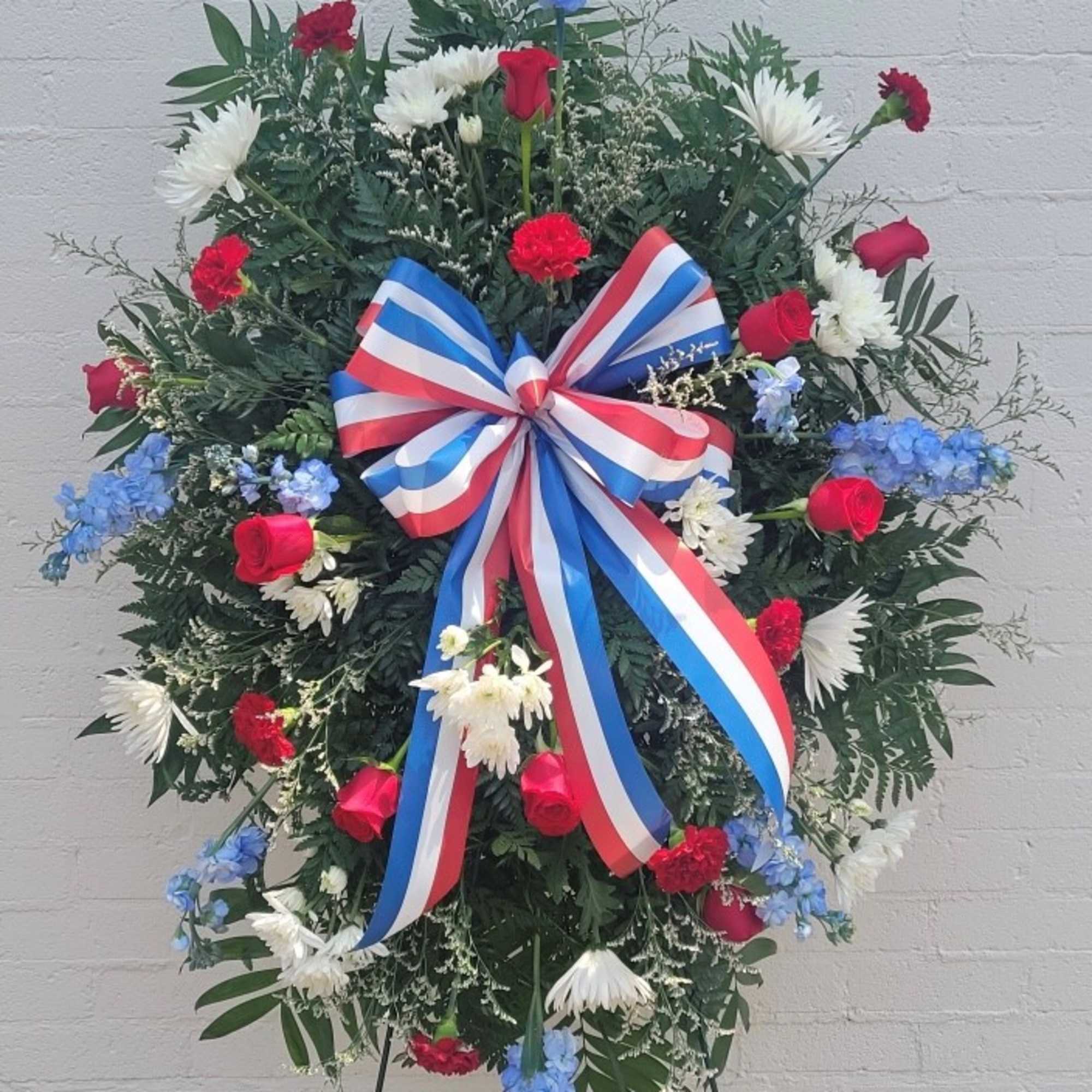 A full circular standing spray that reads as both patriotic and reverent