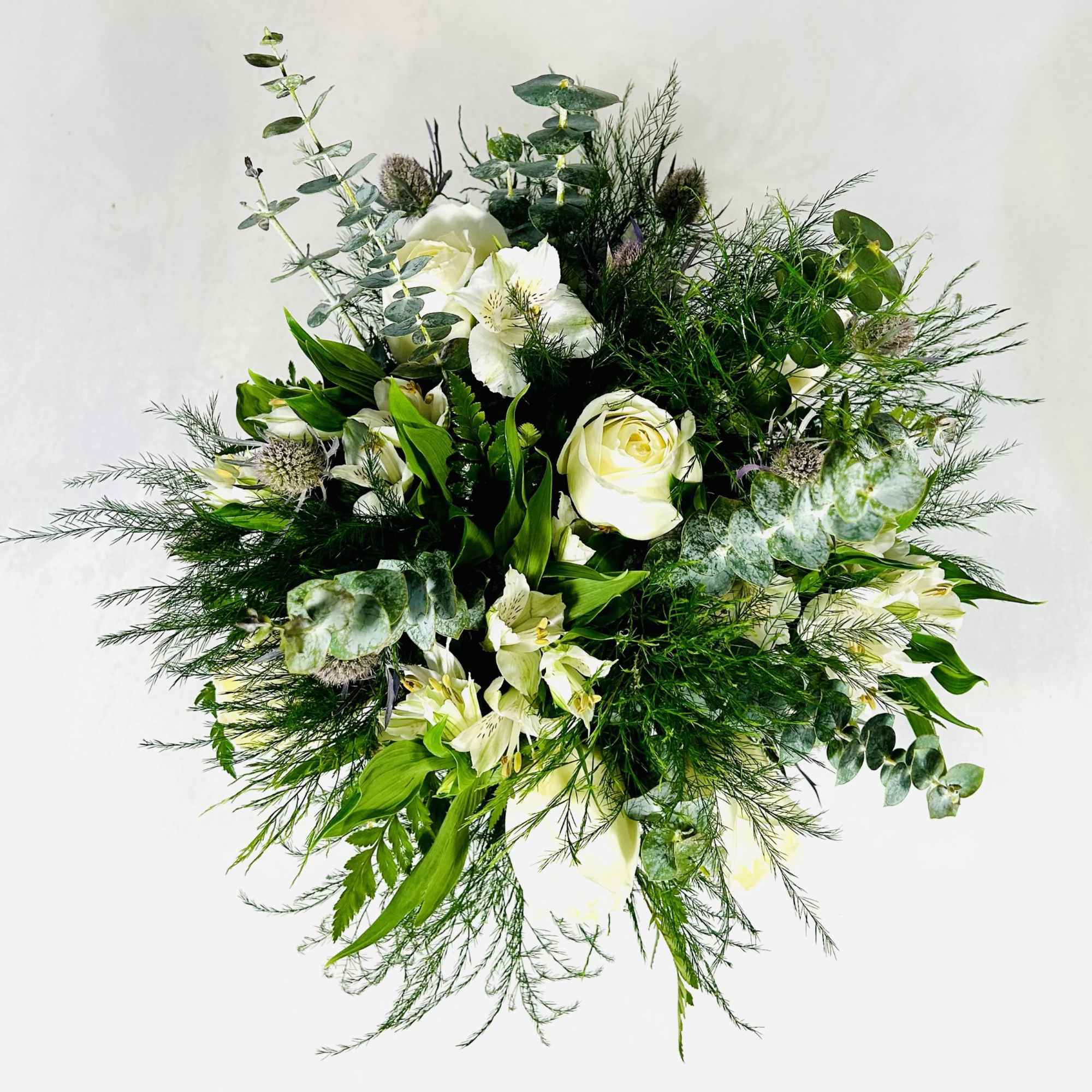 White roses and lilies in a loose green bouquet