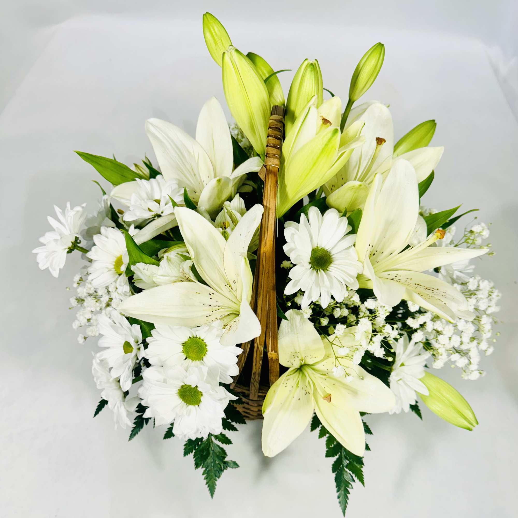 Basket arrangement of white lilies and white daisies