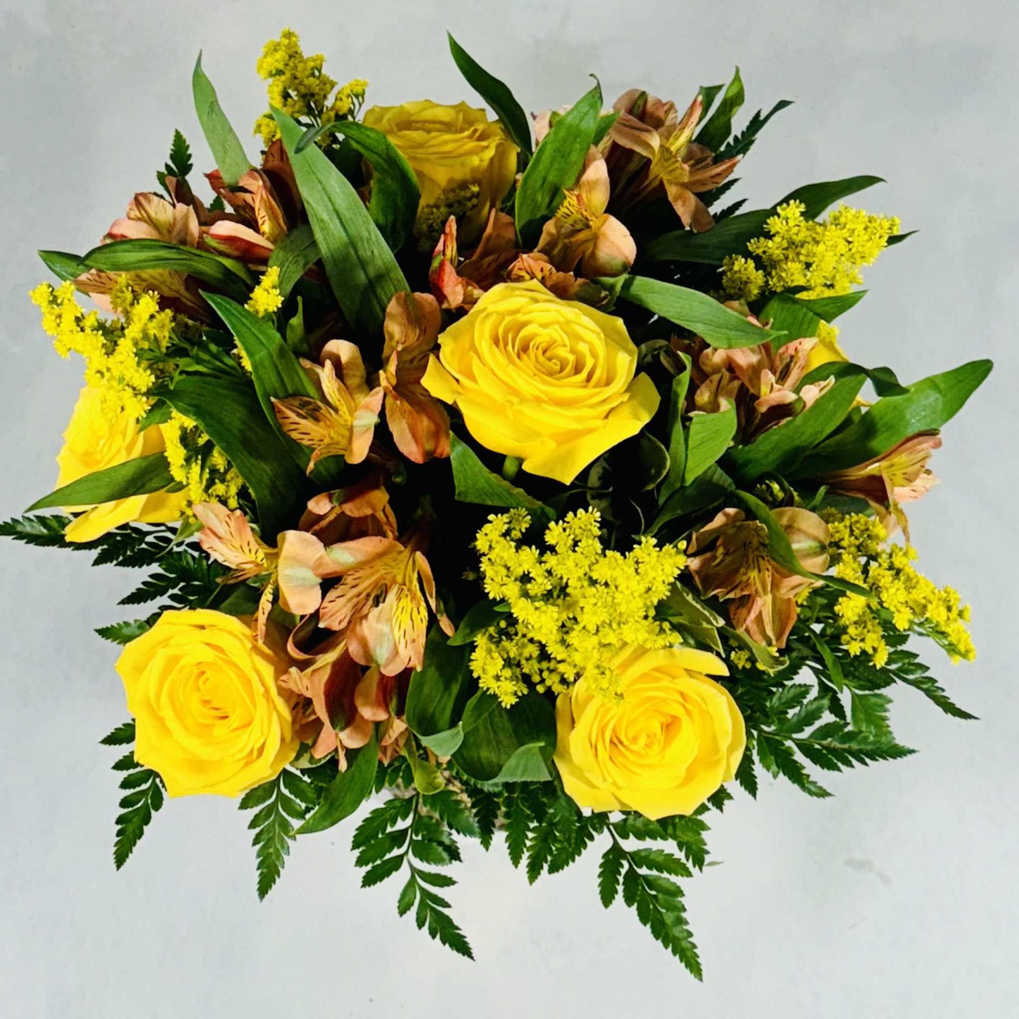 Yellow roses with peach alstroemeria and yellow filler flowers in a bouquet