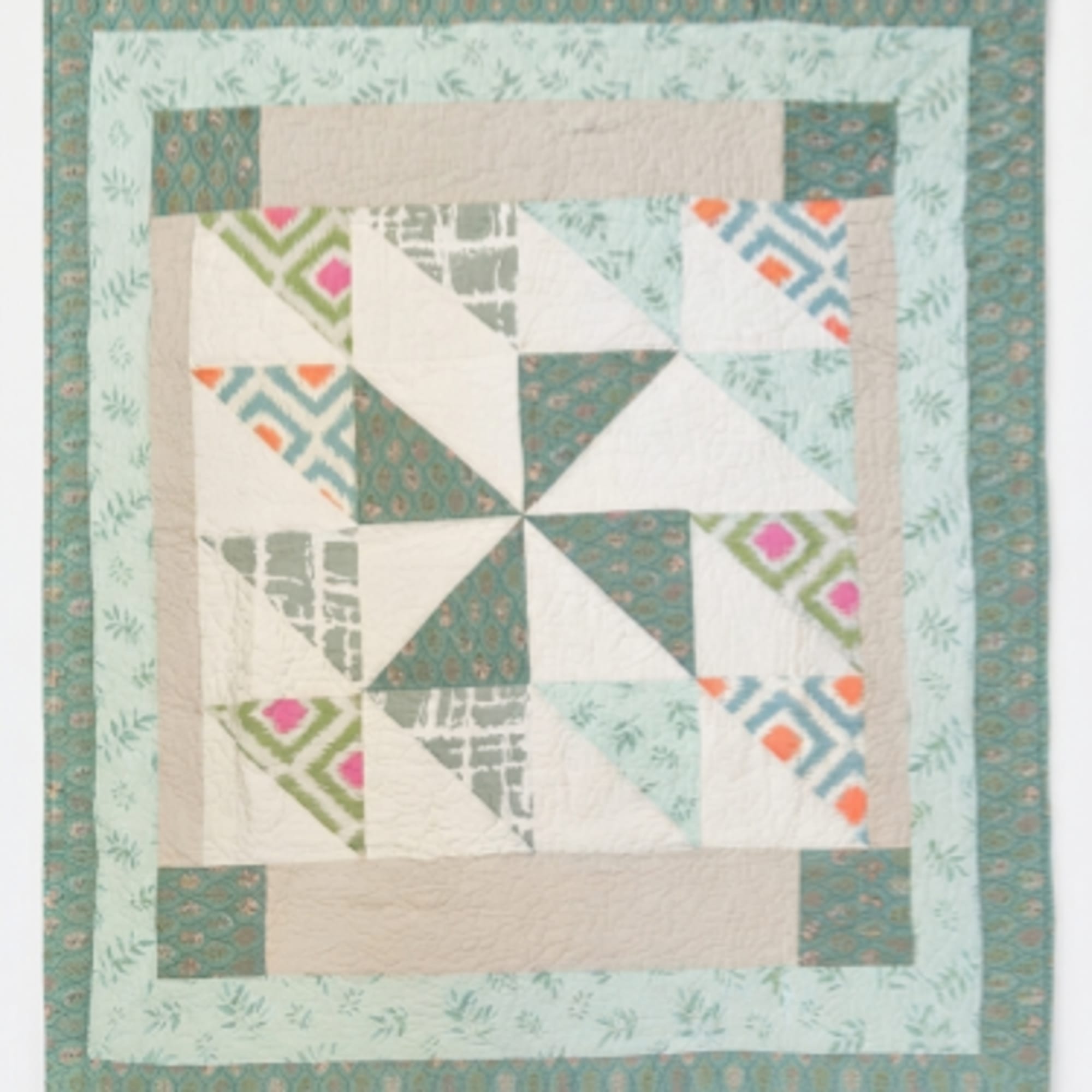 Patchwork quilt with teal, cream, and patterned geometric blocks