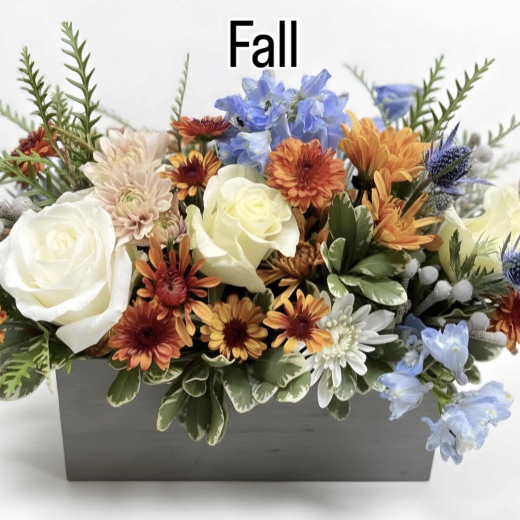 Fall floral arrangement in a rectangular gray container with white roses and mixed blooms