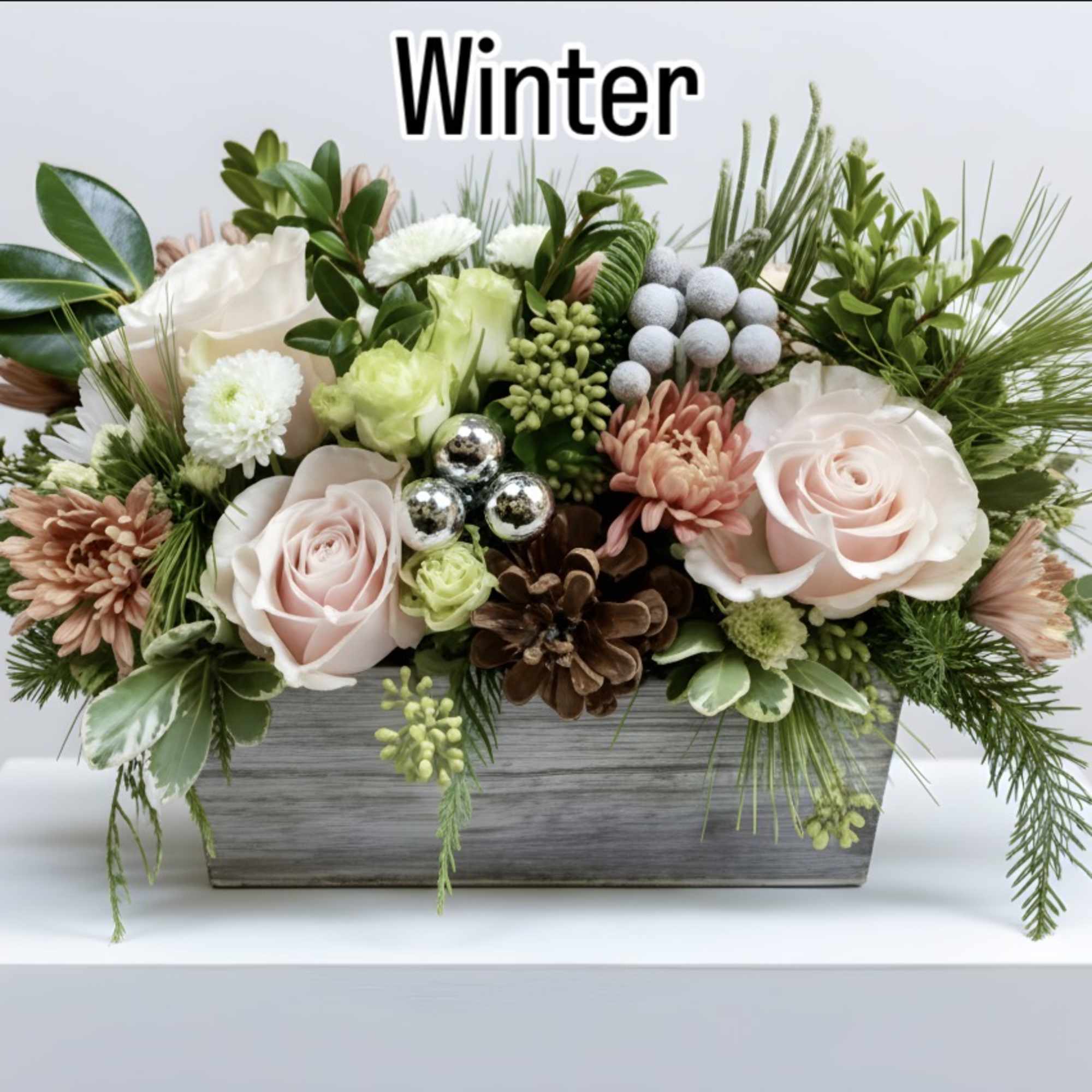 Winter floral arrangement with pale pink roses in a gray wooden planter
