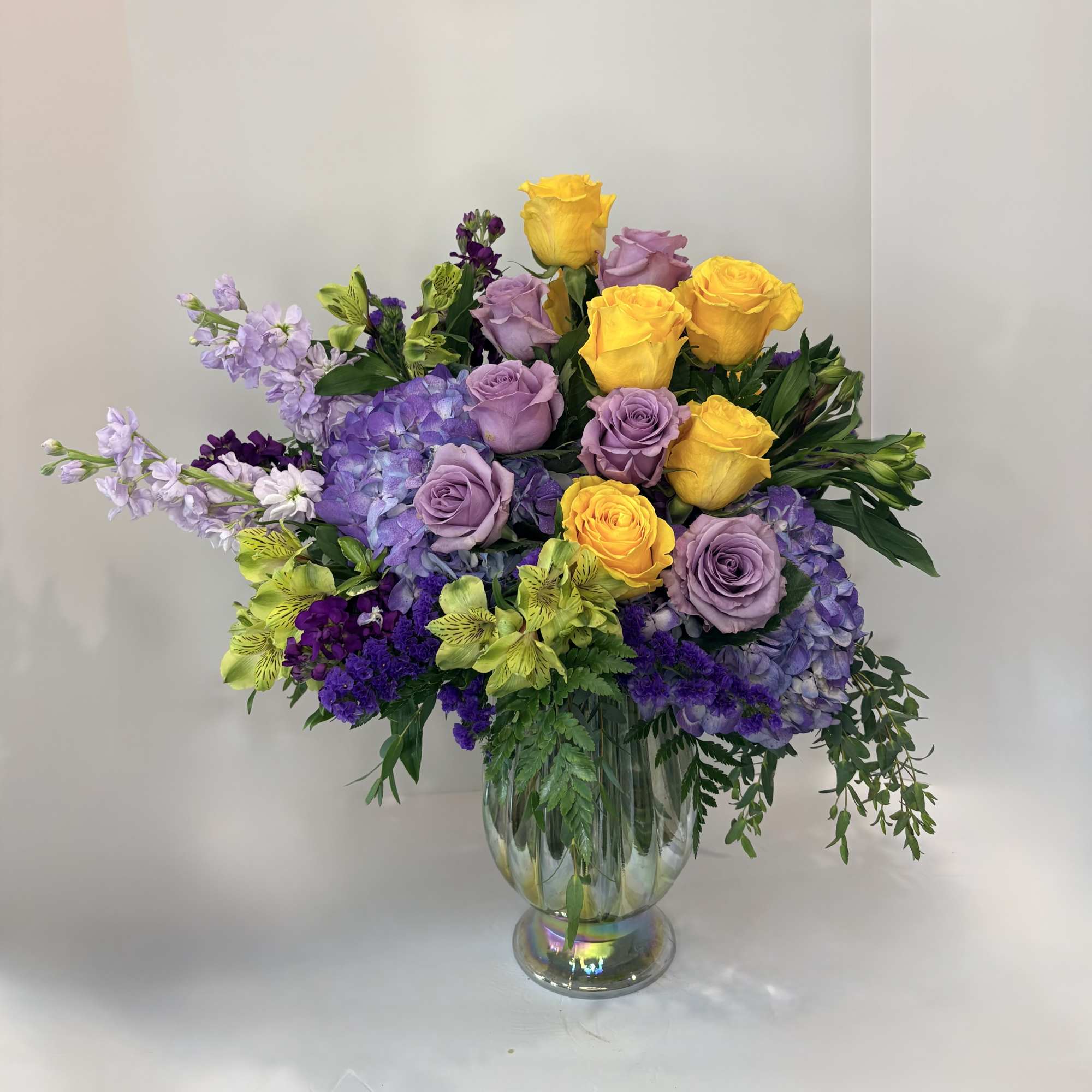 Bouquet of yellow and lavender roses in a clear glass vase