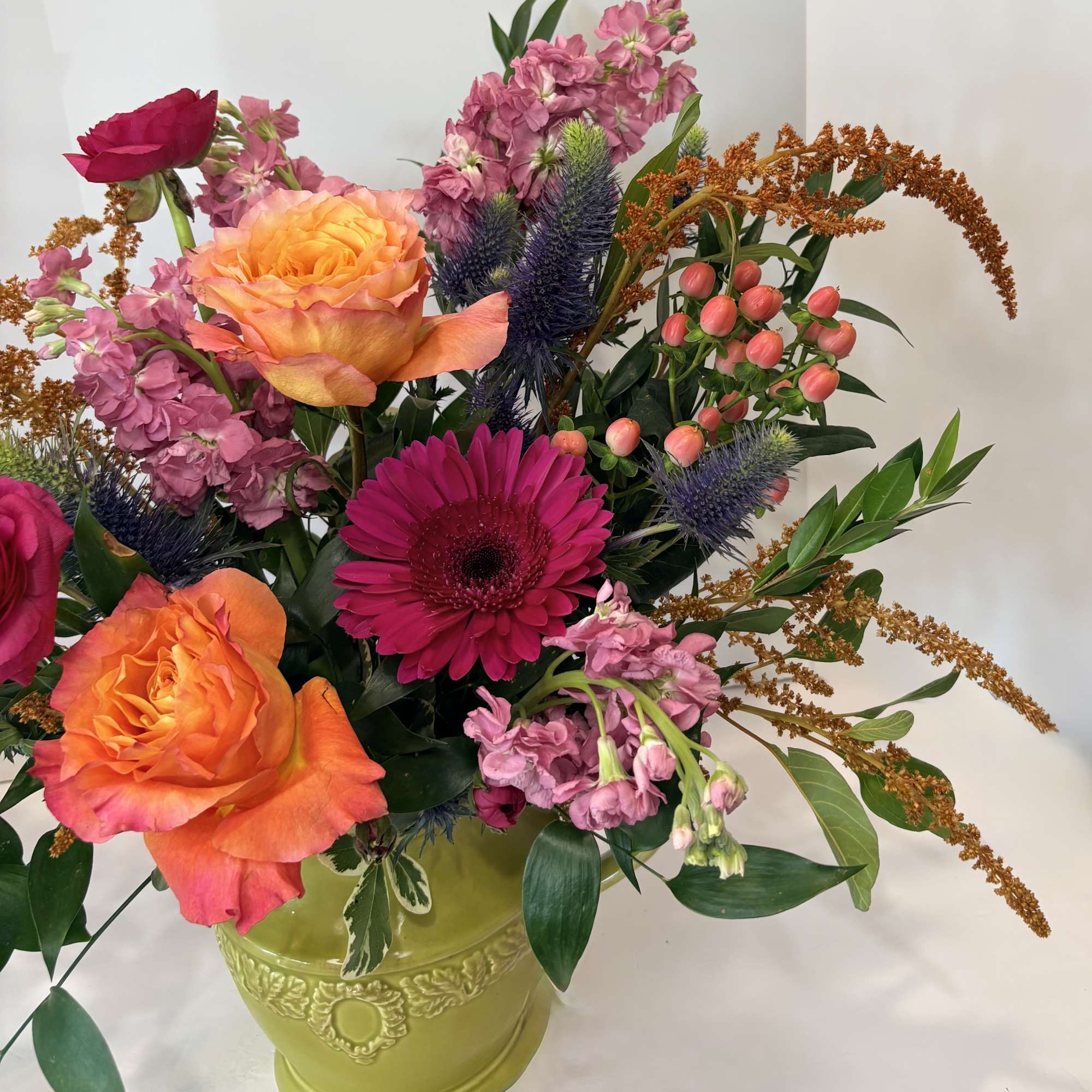 Mixed bouquet with orange and pink roses in a green vase