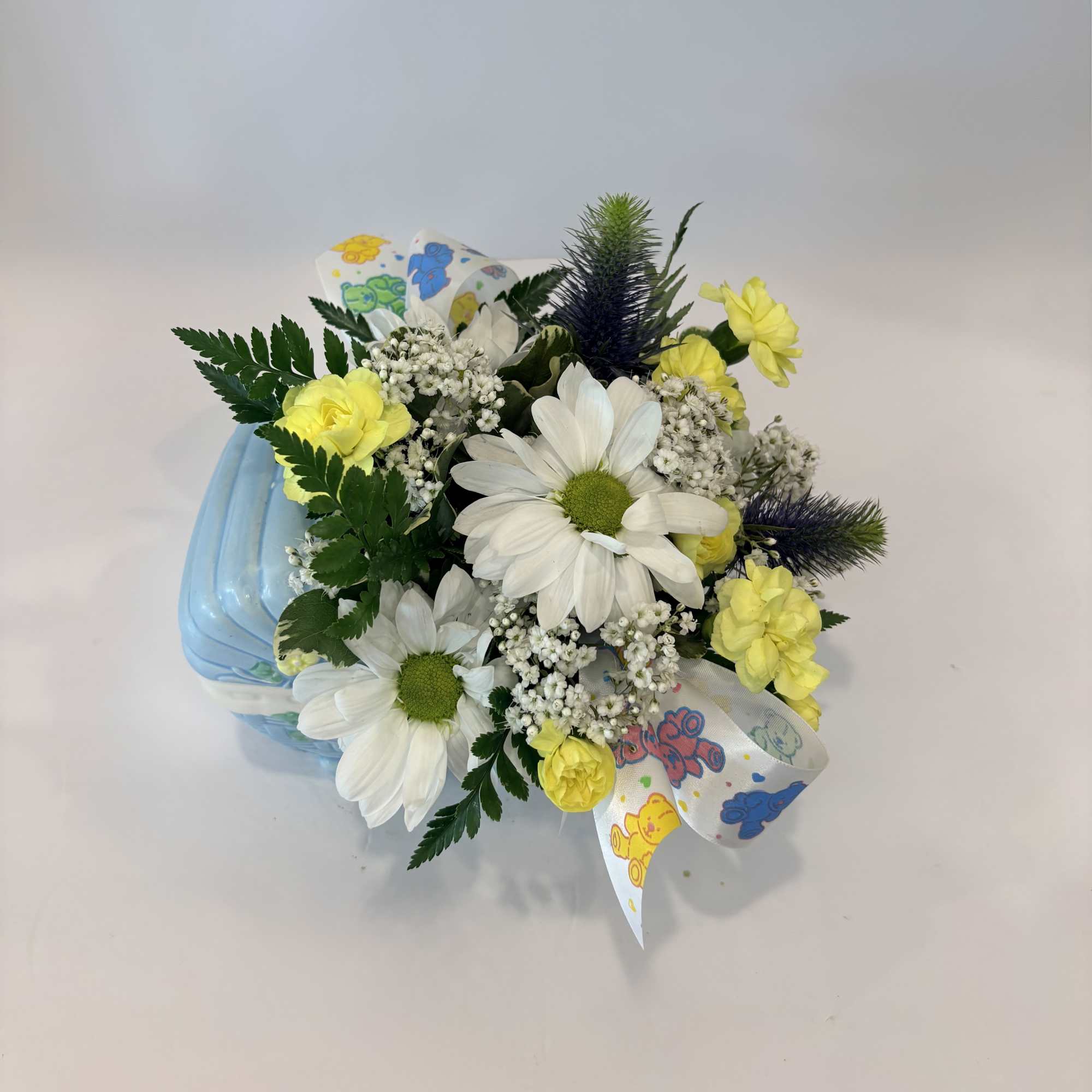 Bouquet of white daisies and yellow flowers in a blue container