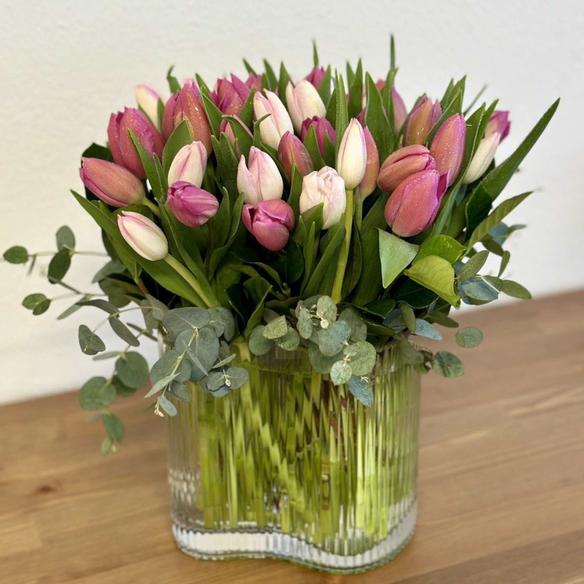 Pink and white tulips in a clear glass vase