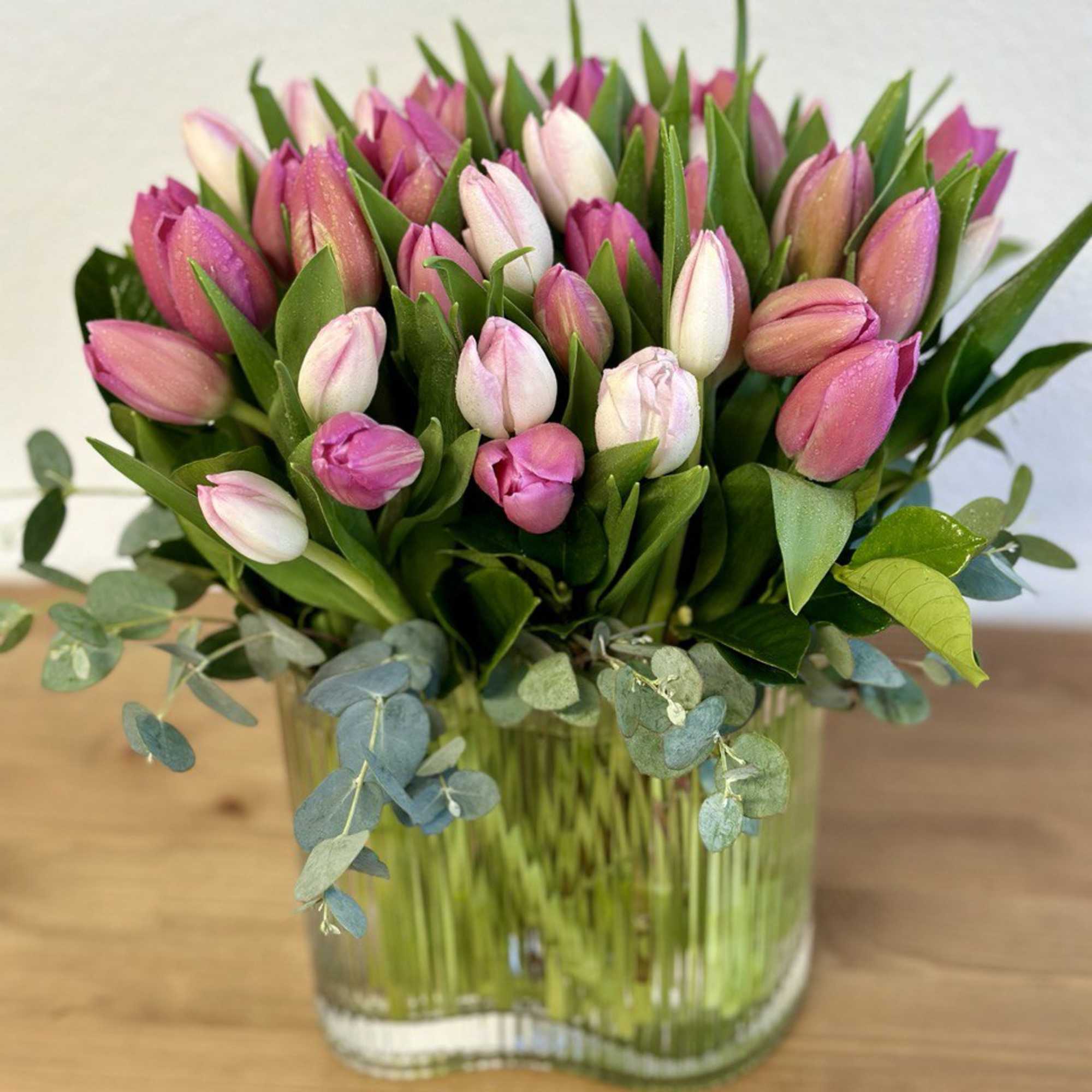 Pink and white tulips arranged in a clear glass vase