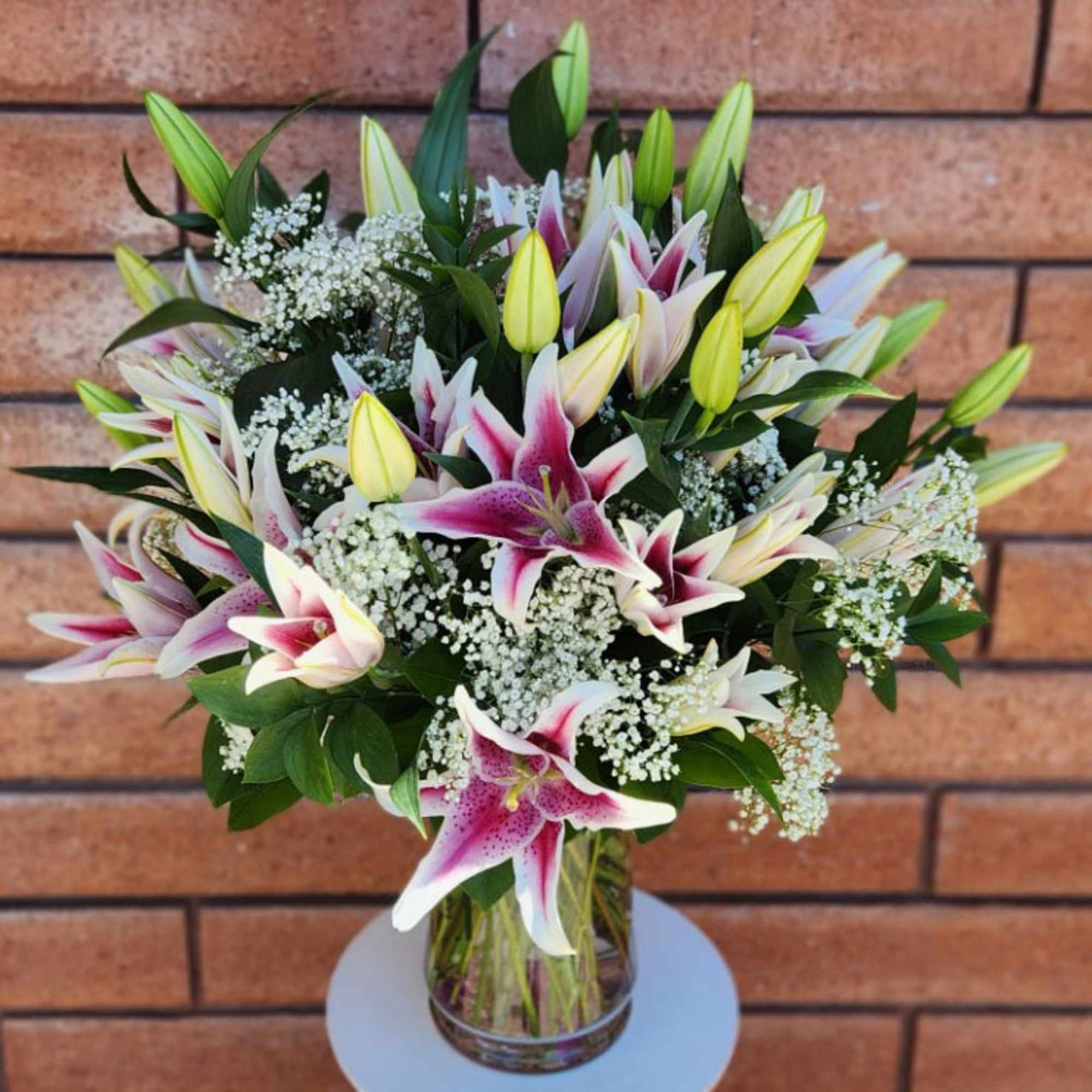 Vase of pink and white lilies with baby’s breath in a clear glass vase