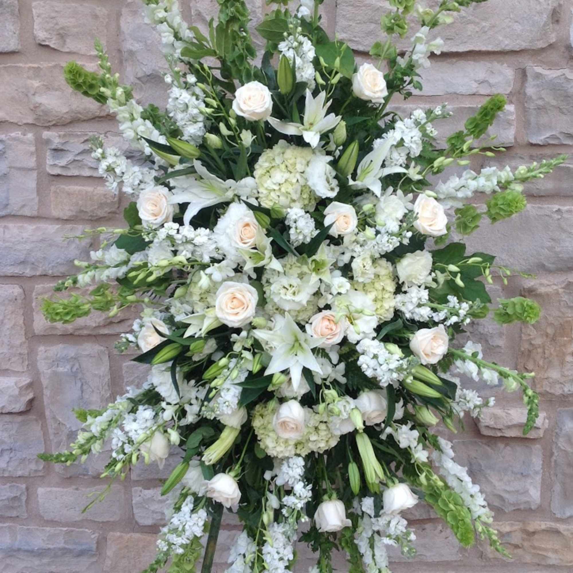 Tall white floral standing spray with roses and lilies on an easel