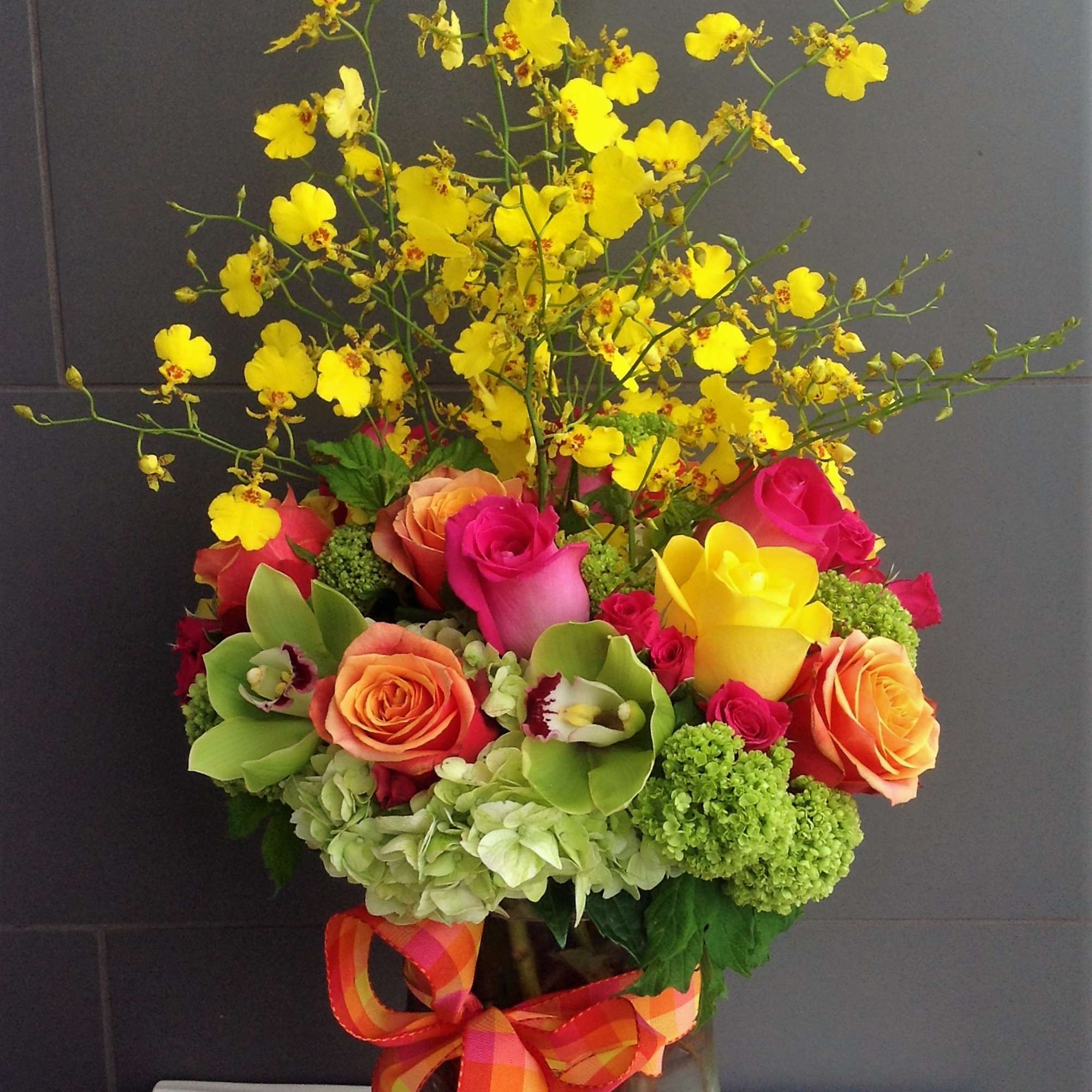 Bright mixed bouquet in a glass vase with a plaid ribbon