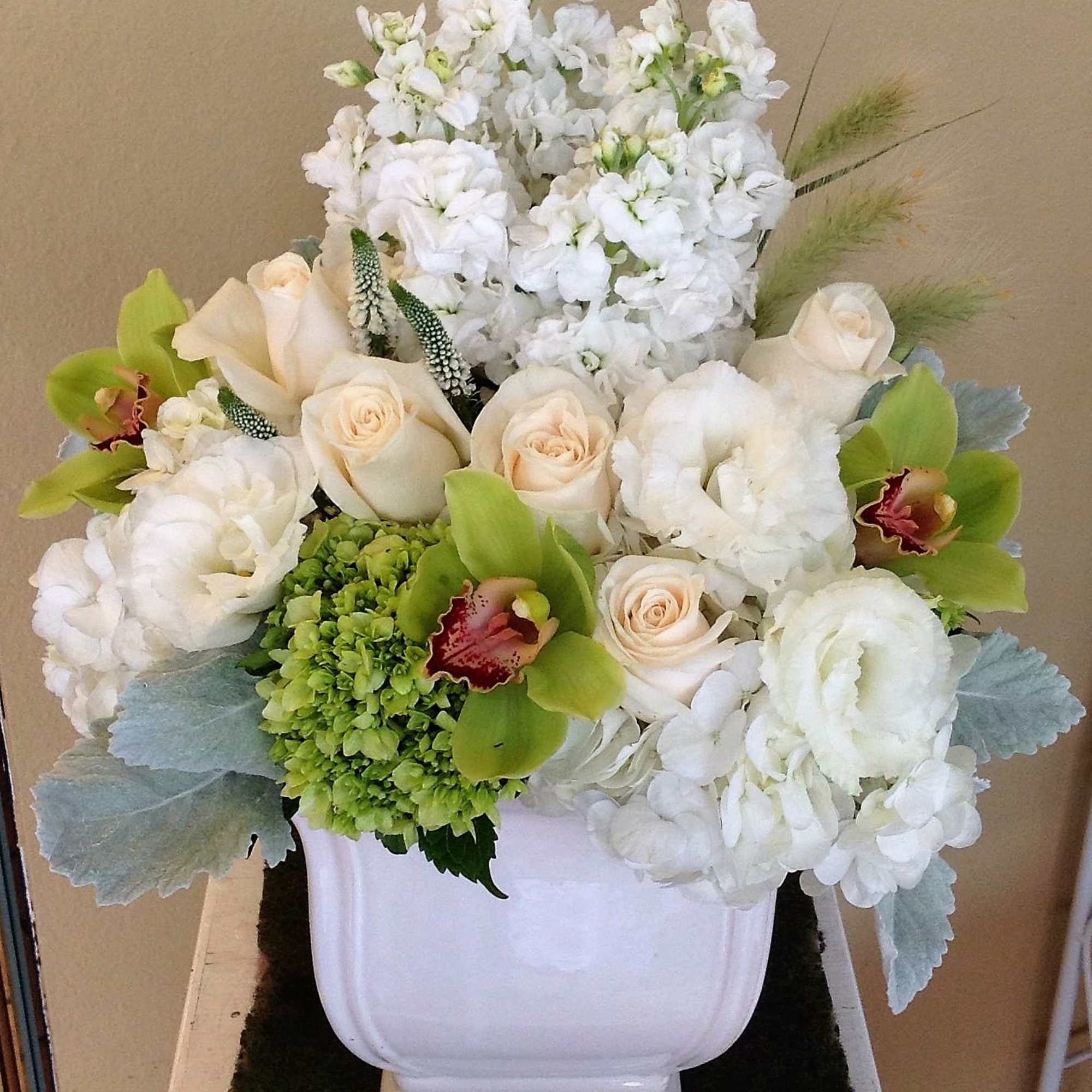 White floral arrangement in a white urn with pale green accents