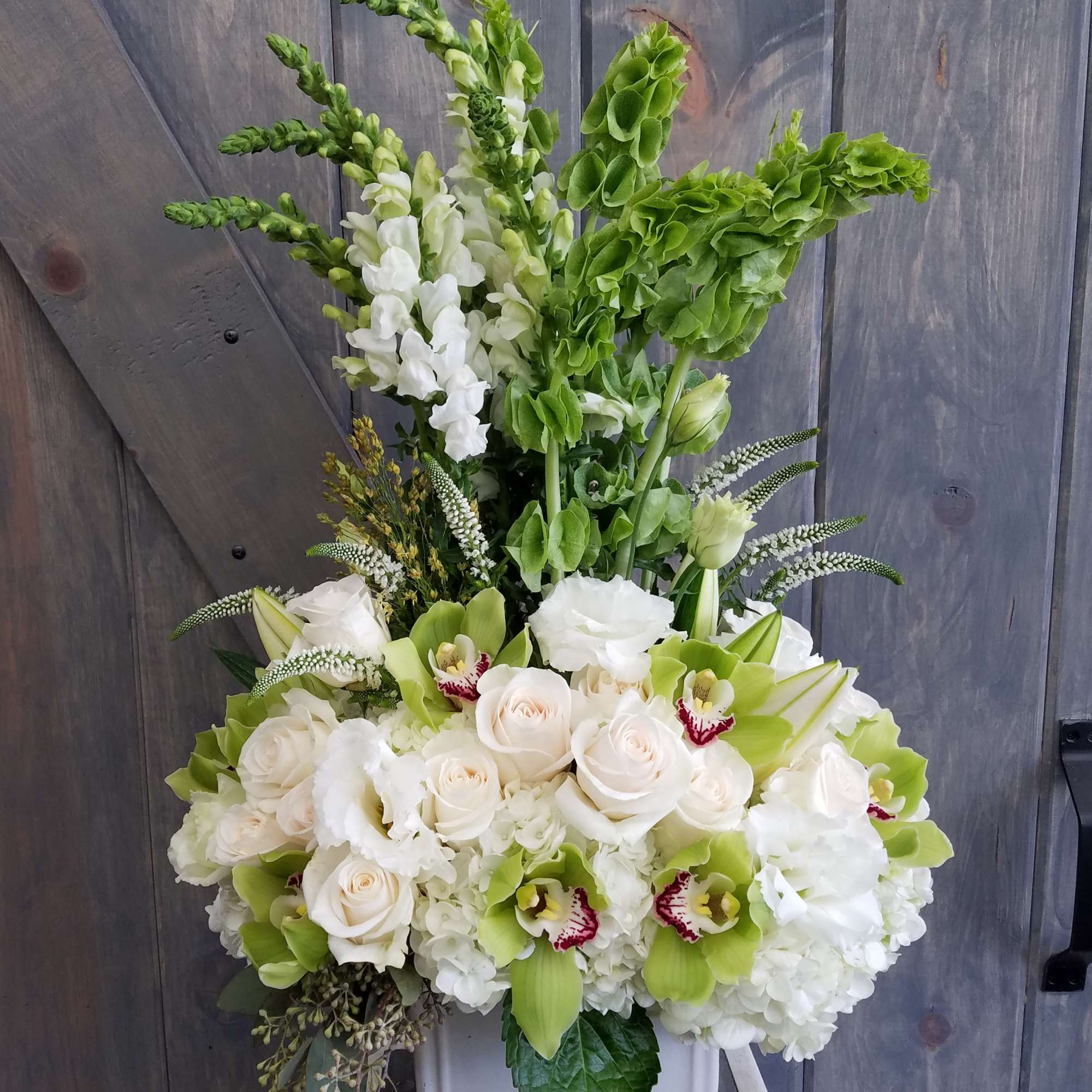 Tall white and green floral arrangement in a white vase