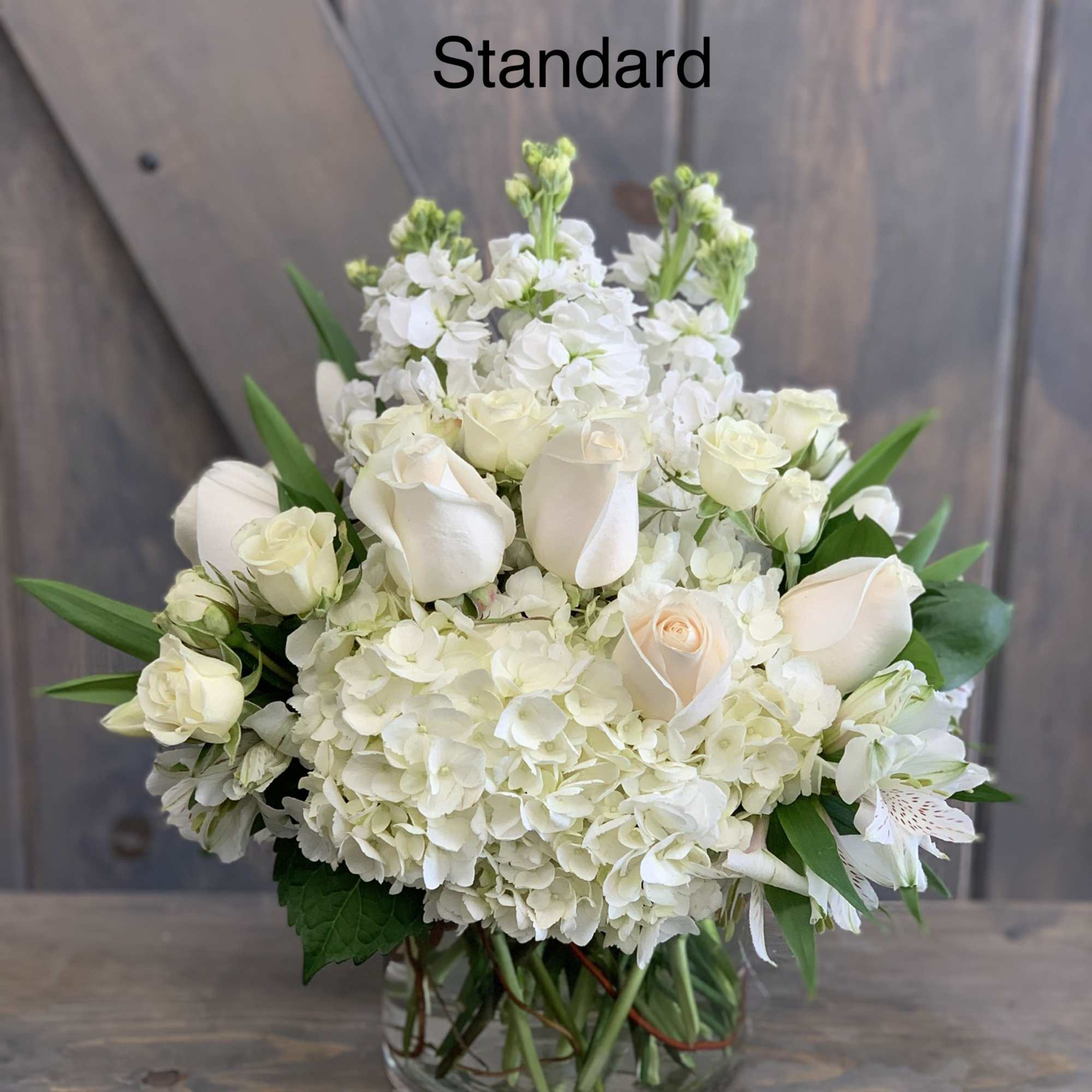 White roses and hydrangeas arranged in a clear glass vase