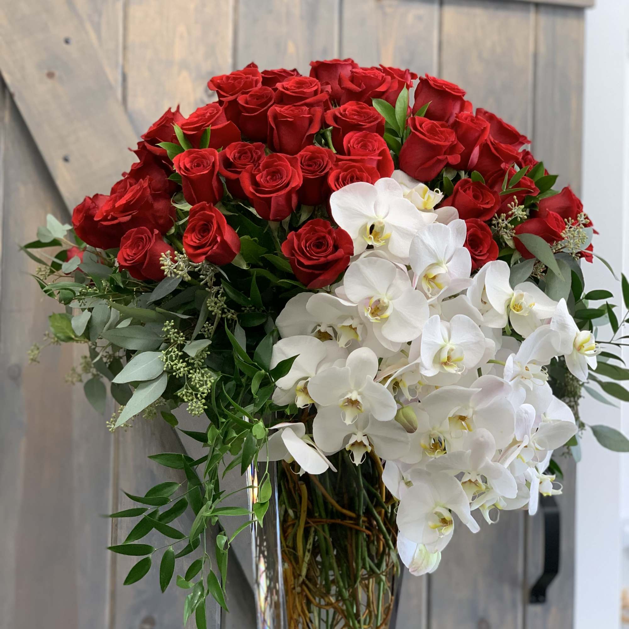 Bouquet of red roses and white orchids in a clear glass vase