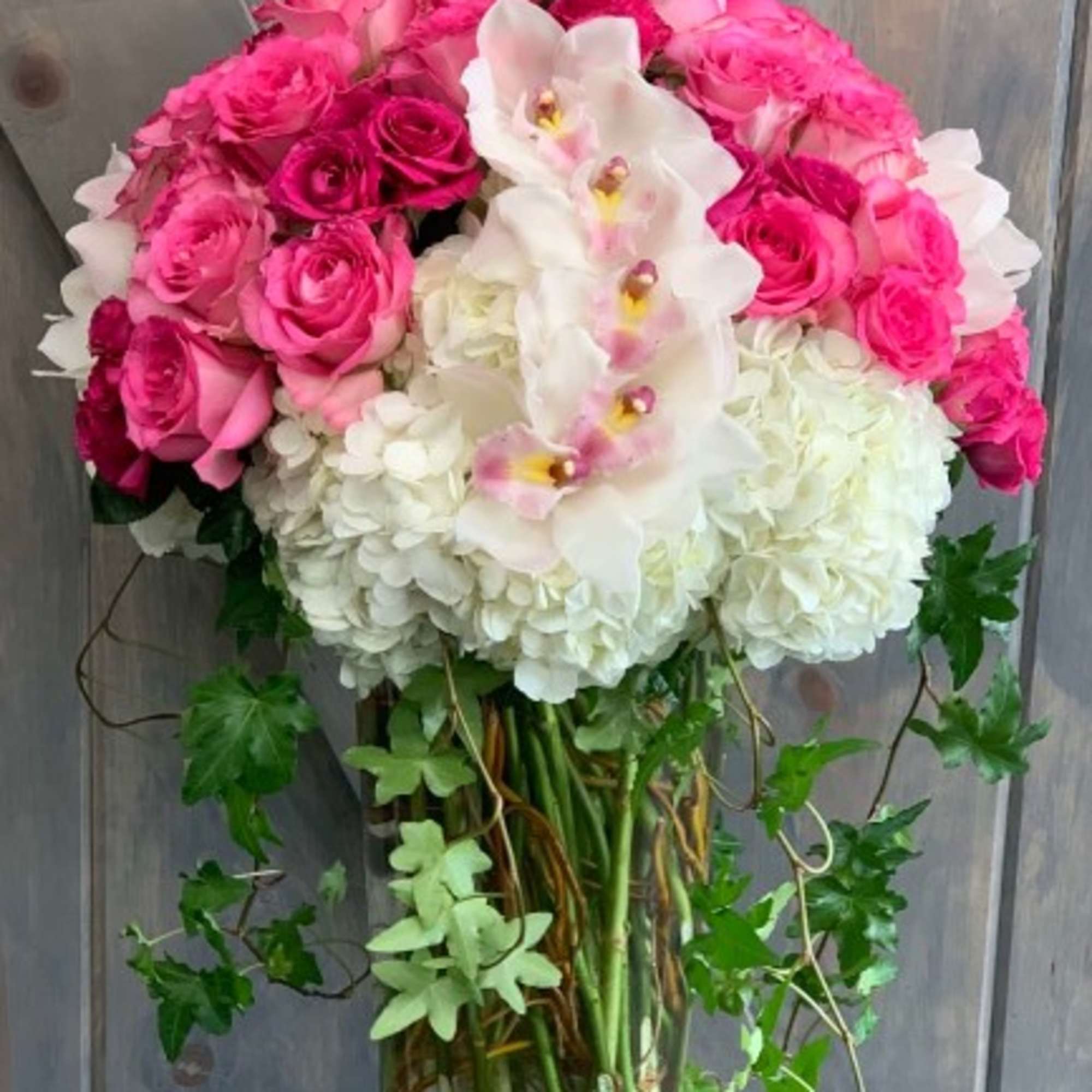 Pink roses and white hydrangeas with orchids in a glass vase