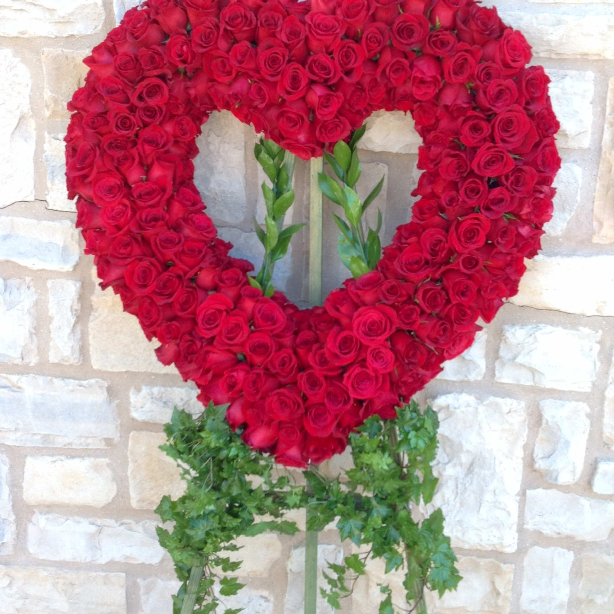 Heart-shaped red rose wreath on a stand