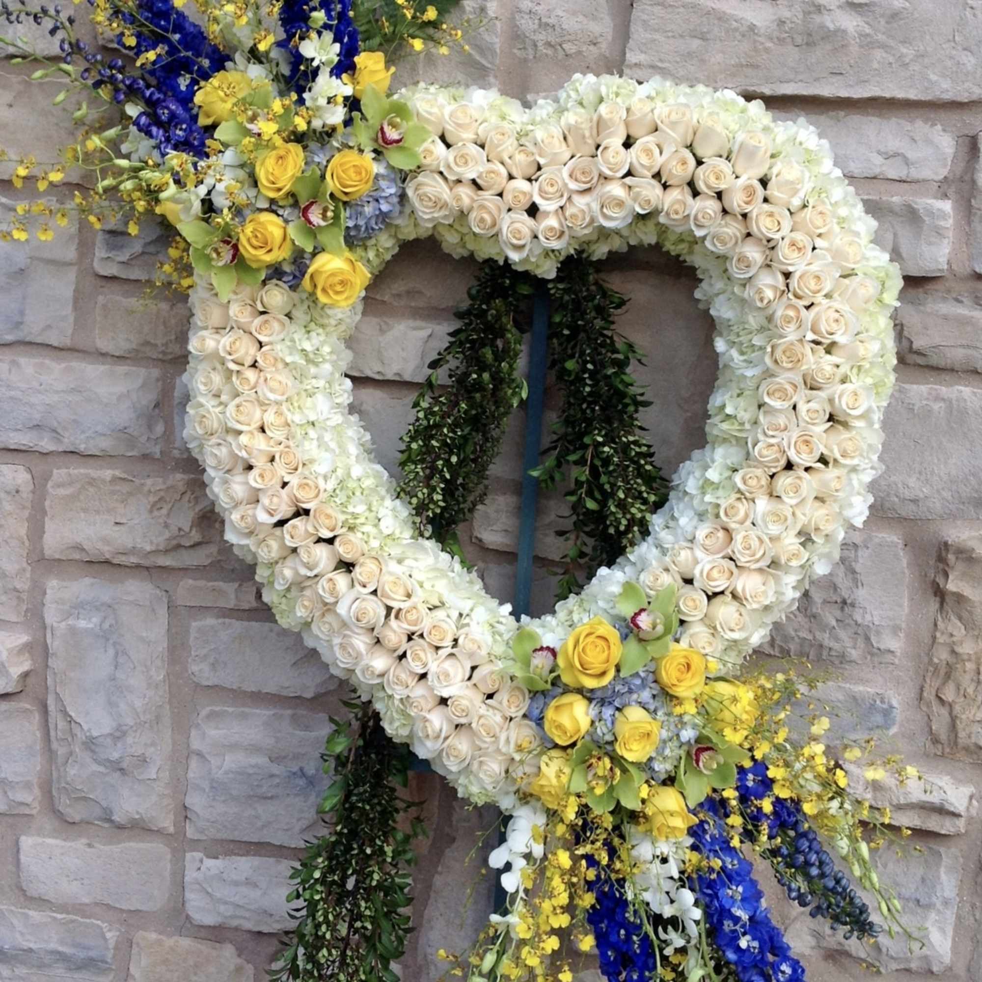 Heart-shaped floral wreath with cream roses and blue and yellow accents