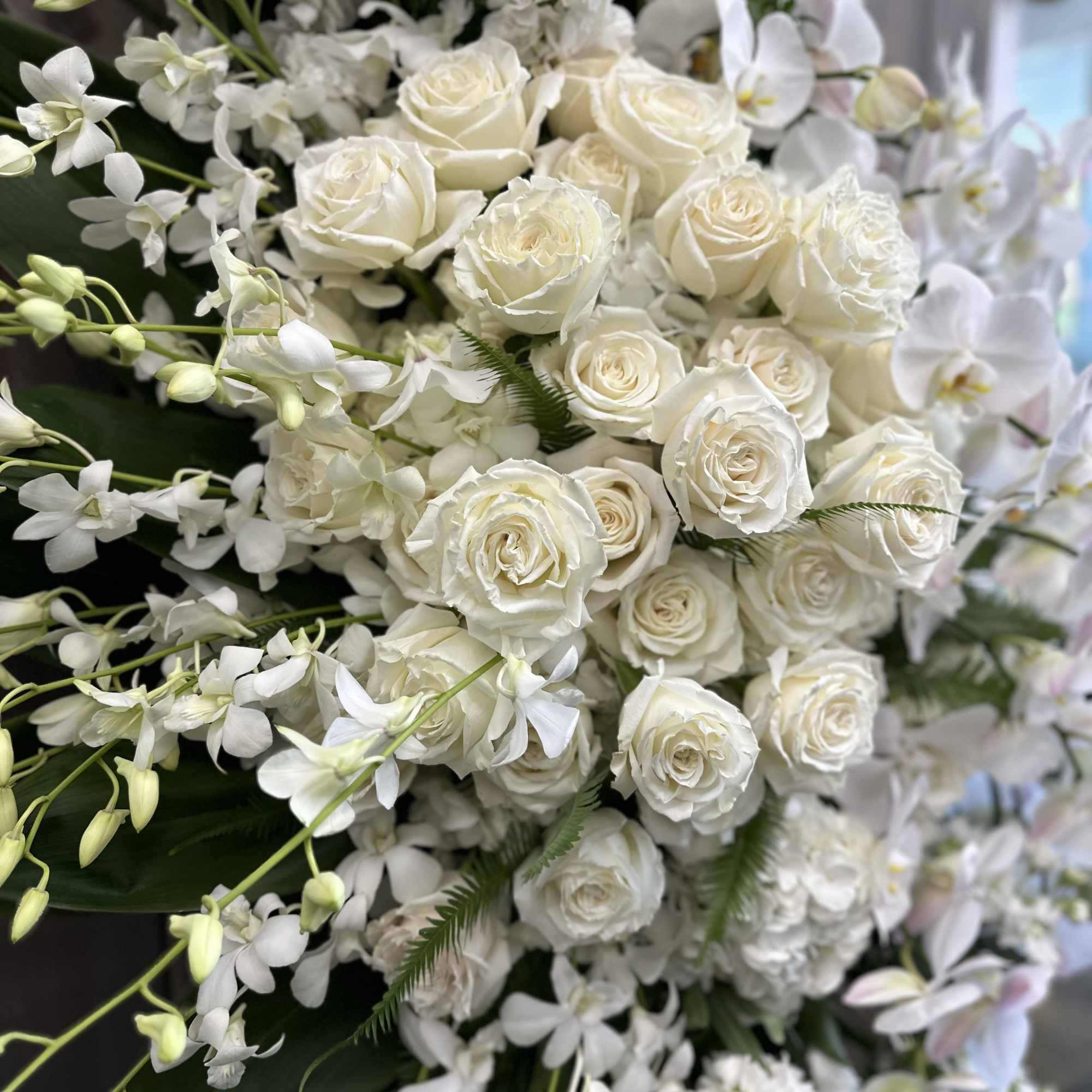 White roses and orchids in a dense floral arrangement