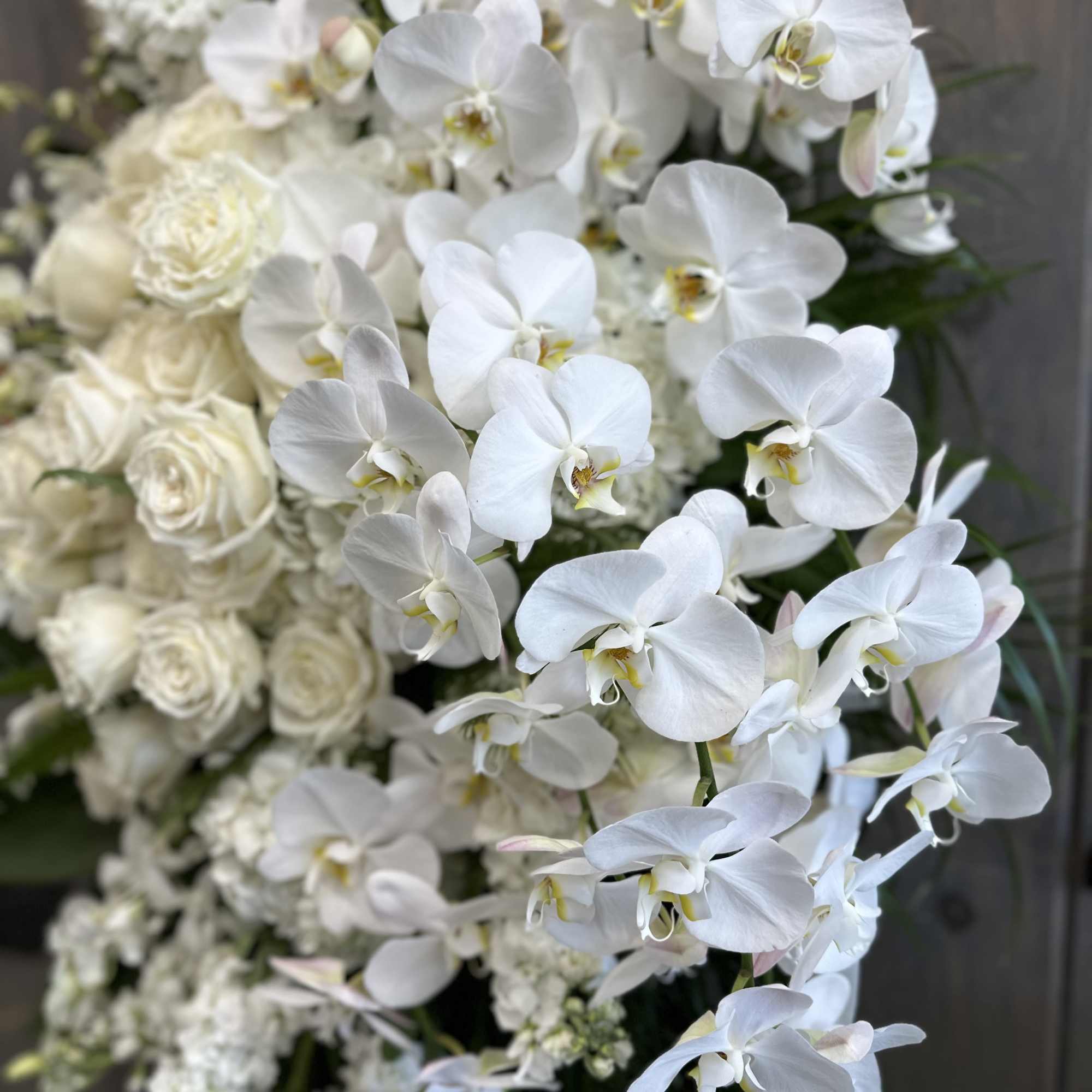 White orchids and roses in a dense floral arrangement