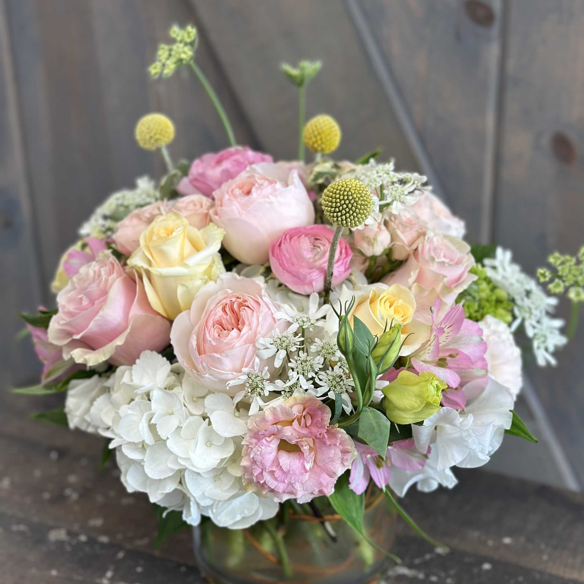 Pastel bouquet of roses, hydrangeas, and mixed blooms in a glass vase