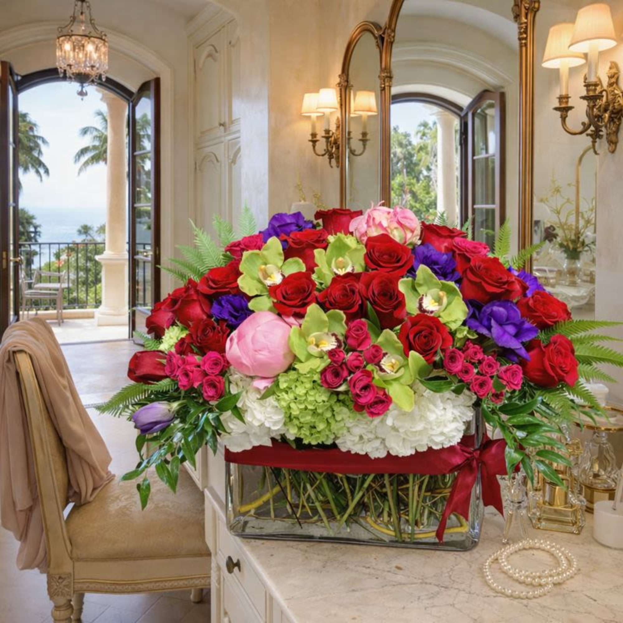 Large mixed bouquet of red, pink, purple, and green flowers in a glass vase