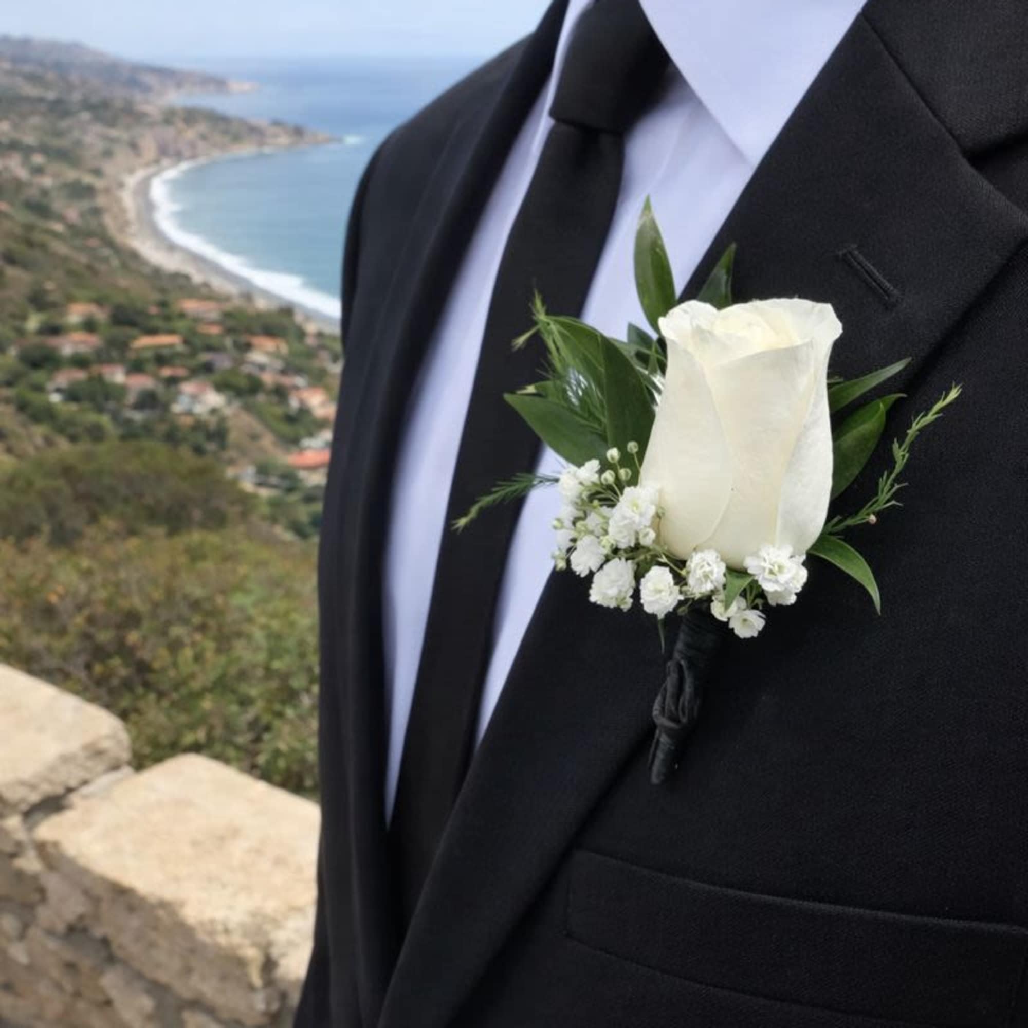 White rose boutonniere on a black suit jacket
