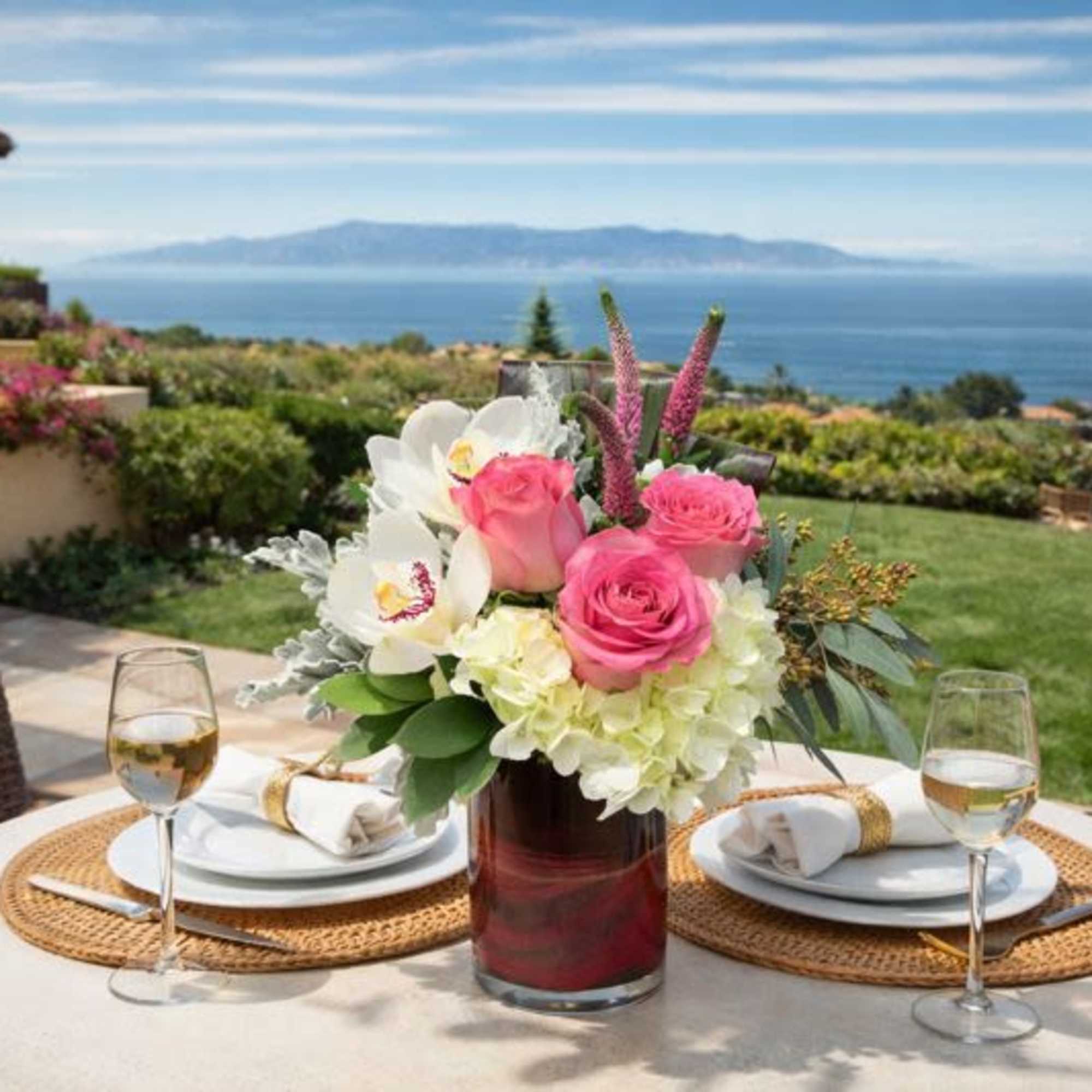 Pink and white floral centerpiece in a glass vase on an outdoor table