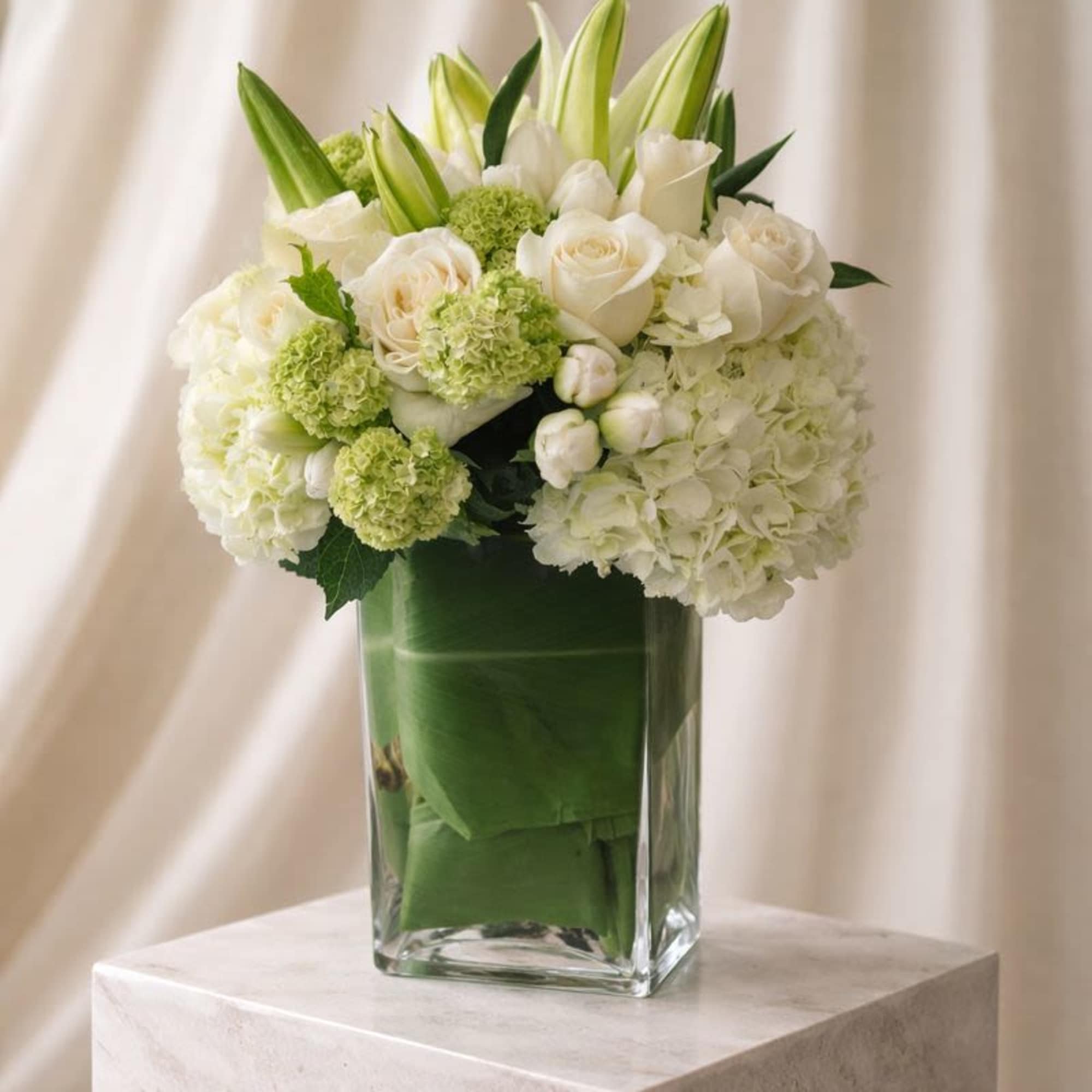 White roses and lilies arranged in a clear glass vase