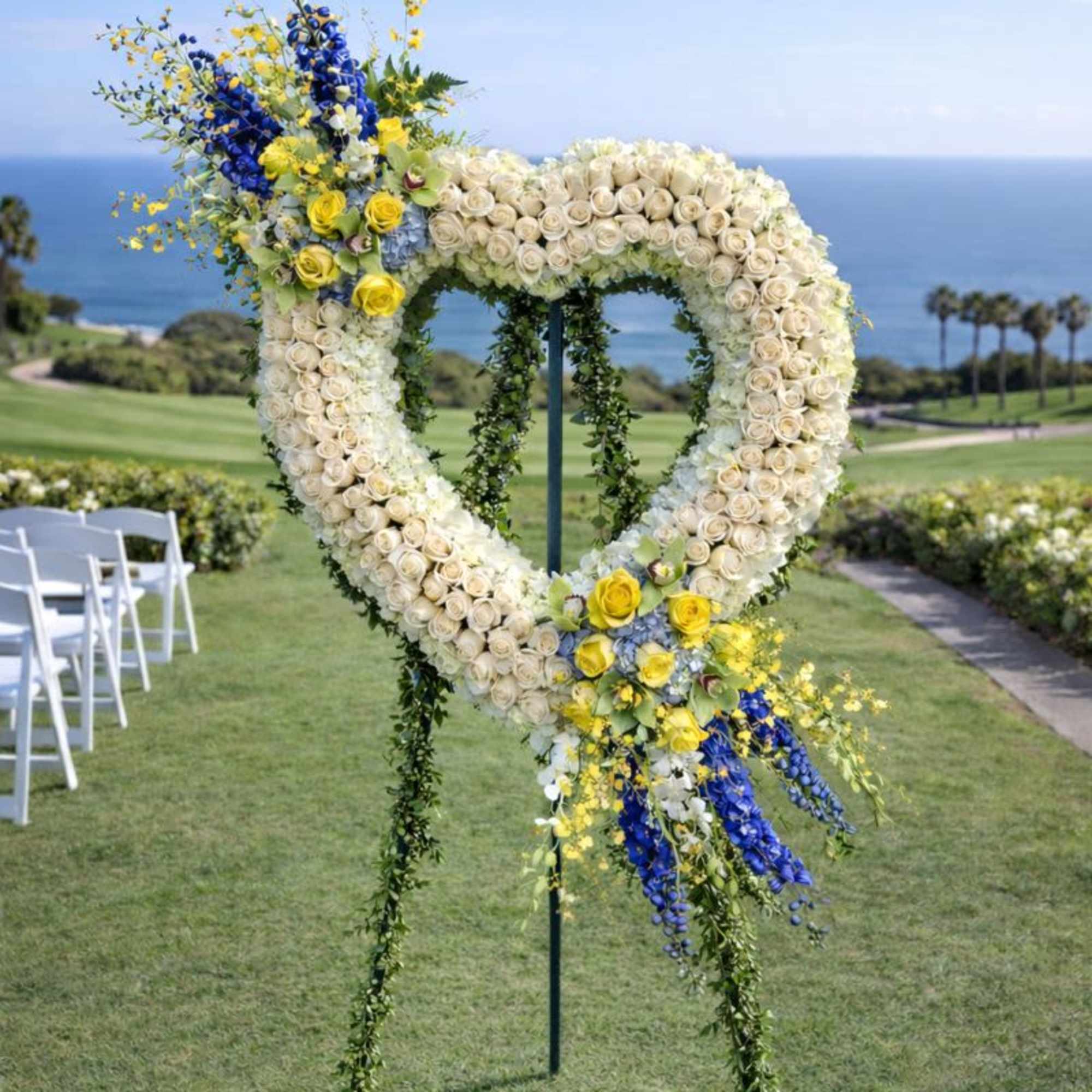 Heart-shaped floral wedding arch with white, yellow, and blue flowers