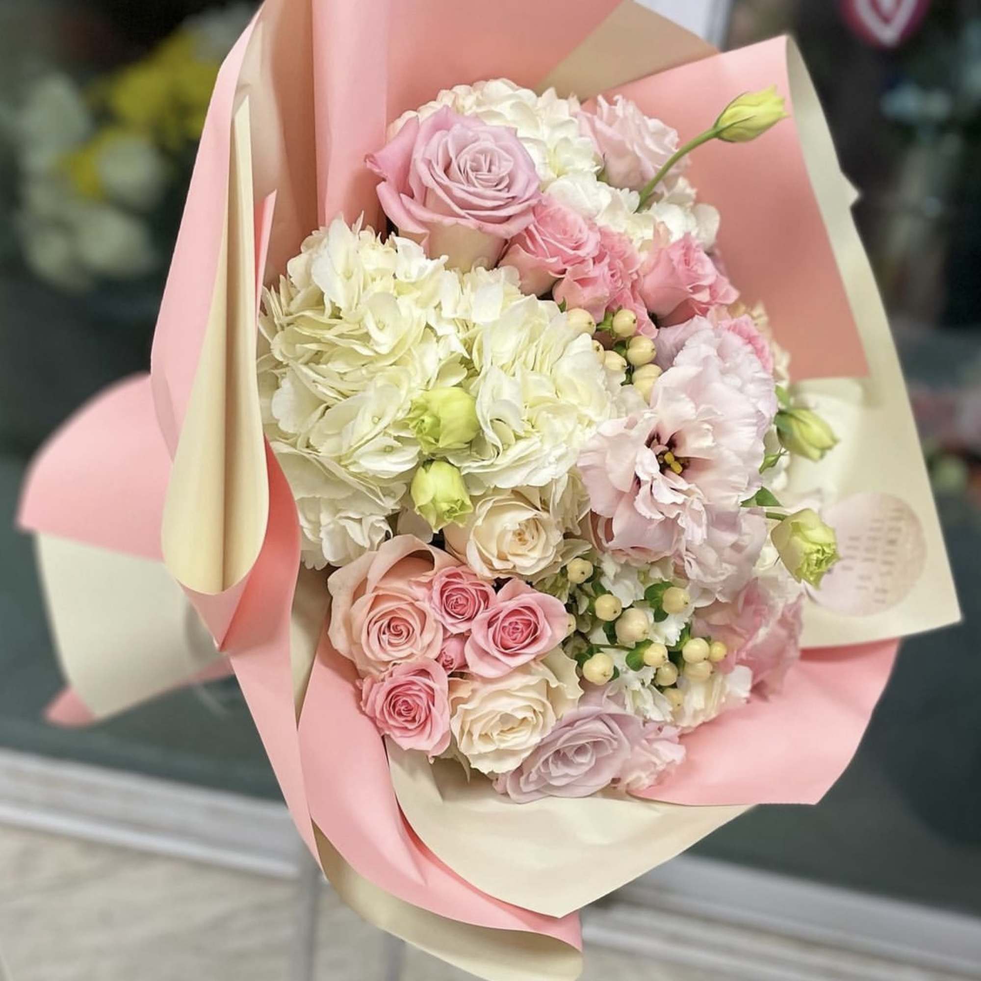 Pink and white bouquet of roses, hydrangeas, and lisianthus in pastel wrap