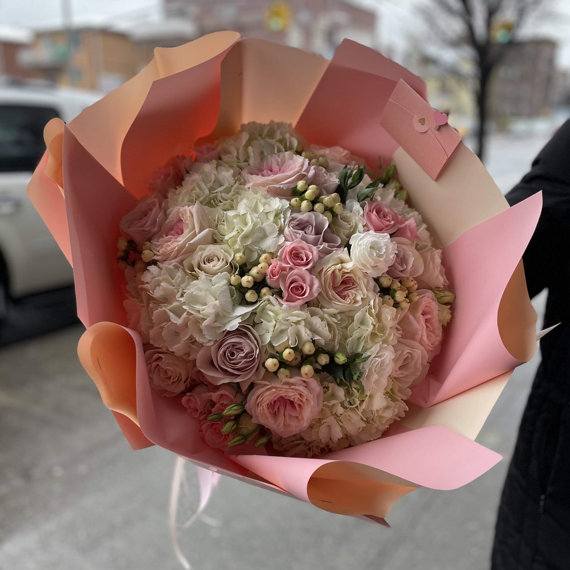 Pink and white bouquet of roses and hydrangeas wrapped in pastel paper