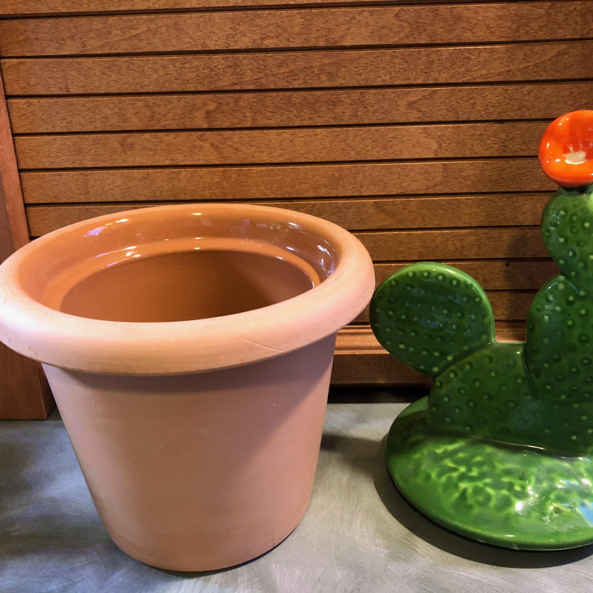 Empty terracotta planter beside a cactus-shaped ceramic sculpture