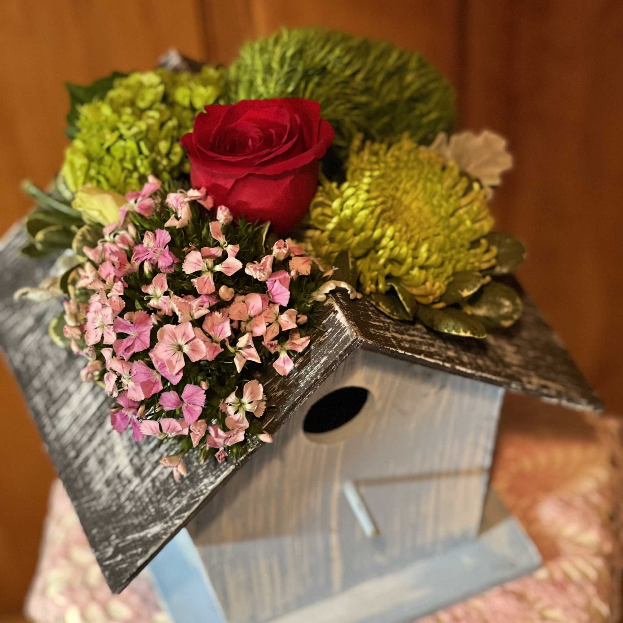 Birdhouse planter topped with a red rose and pink flowers
