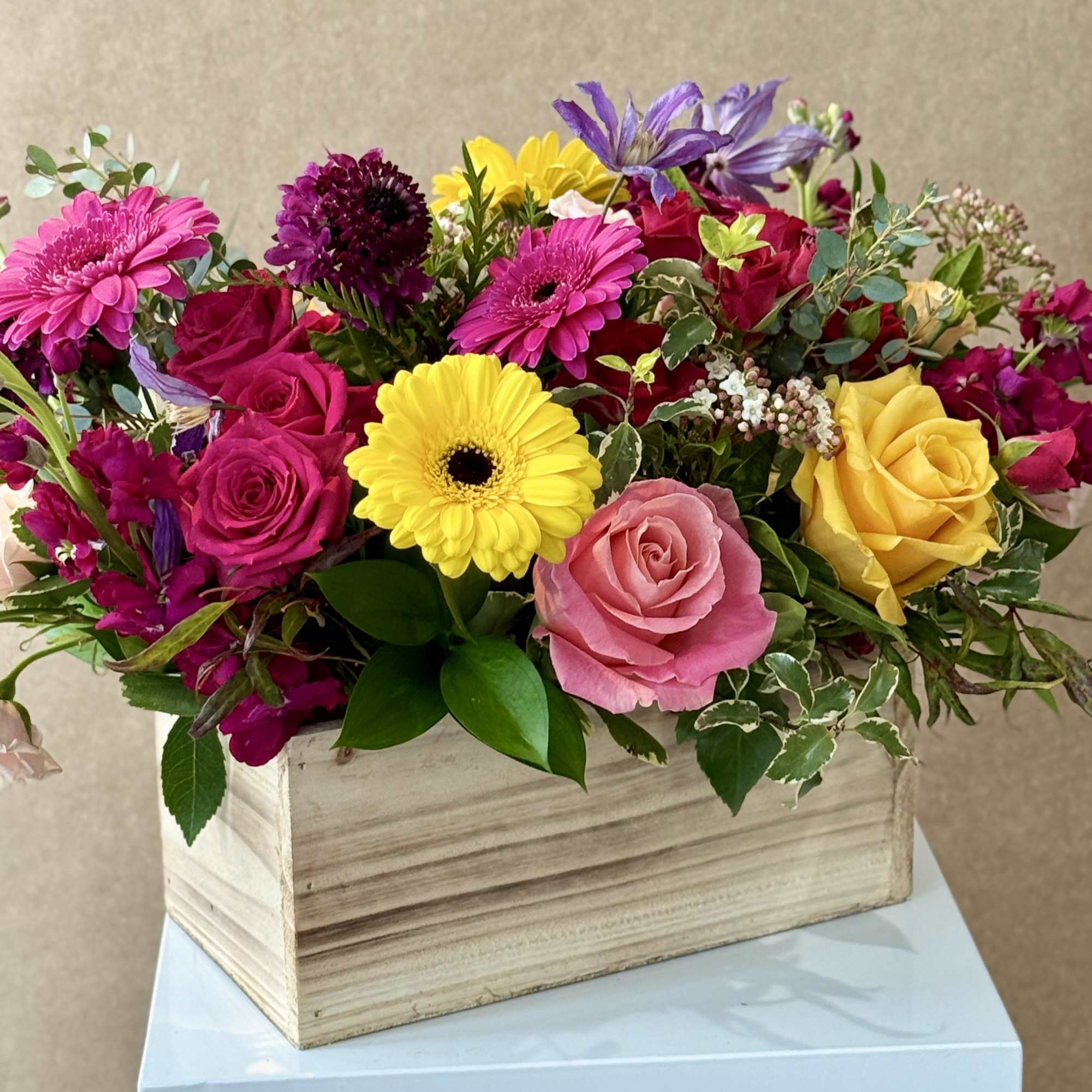 Mixed bouquet in a wooden box with roses, gerbera daisies, and purple blooms
