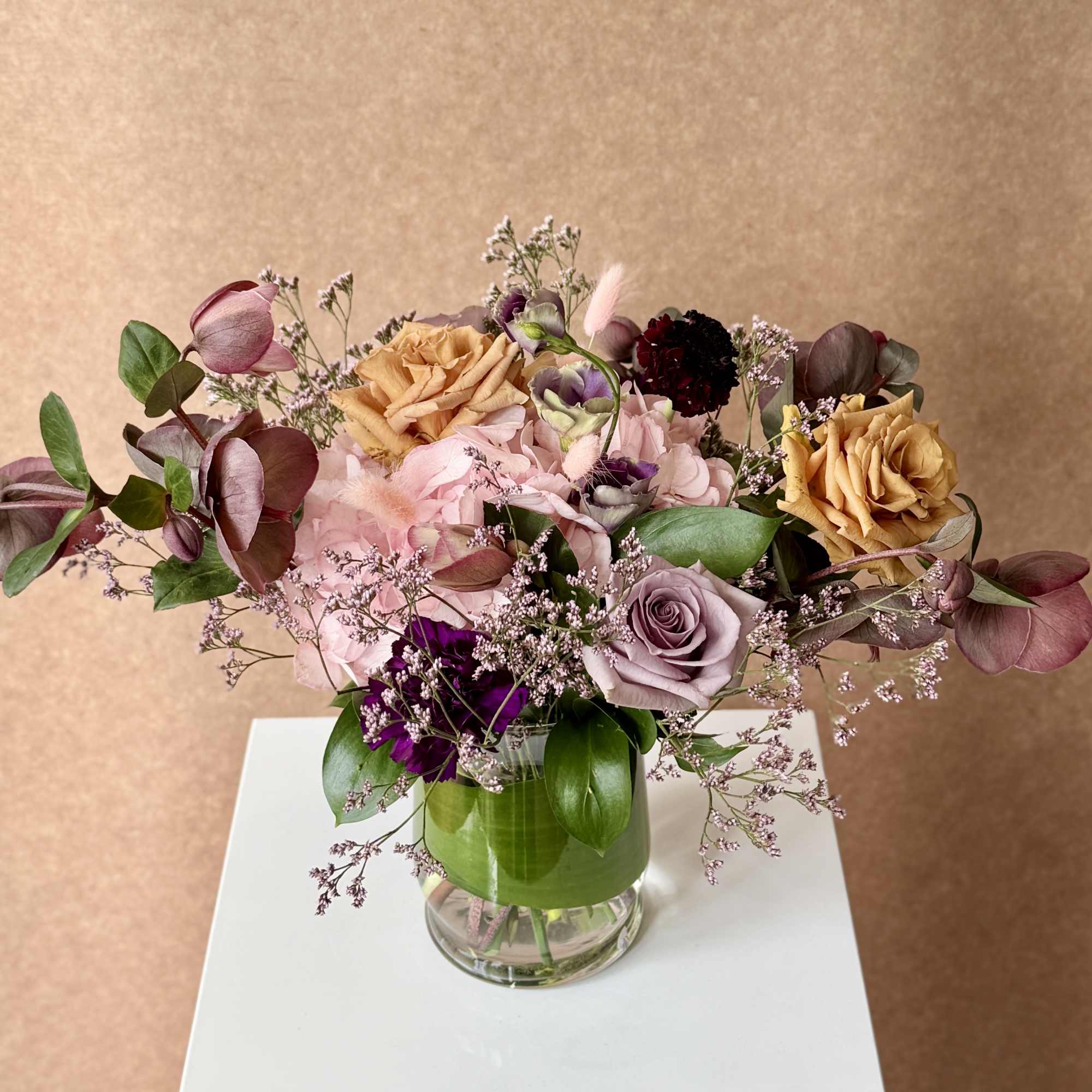 Mixed bouquet of roses and pink blooms in a glass vase
